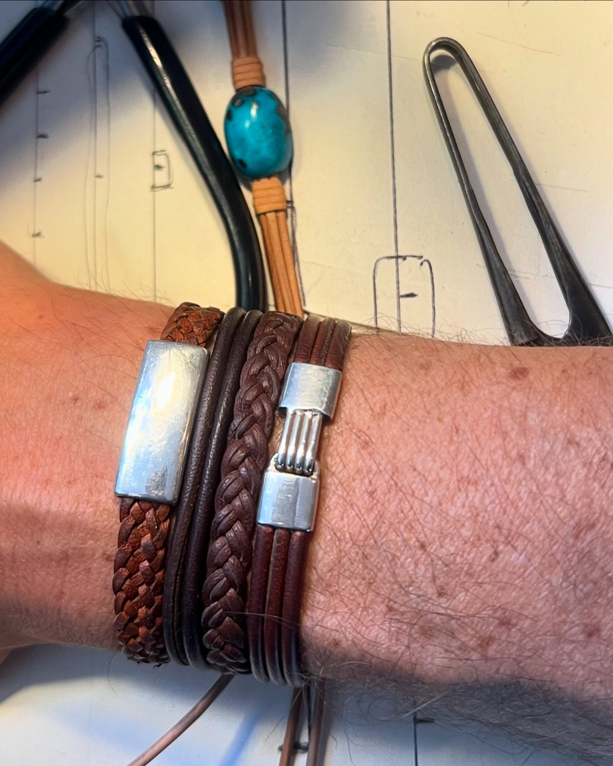 Sterling silver bar bracelet on braided leather worn on wrist, workshop