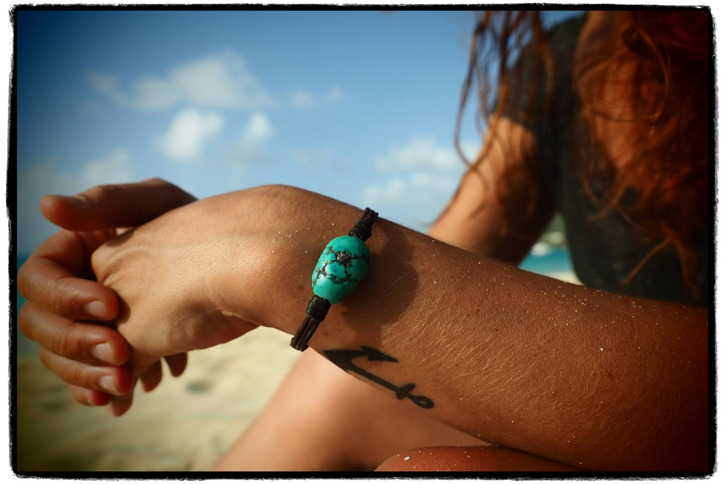 Turquoise bead bracelet on wrist, relaxing on a St Barth beach
