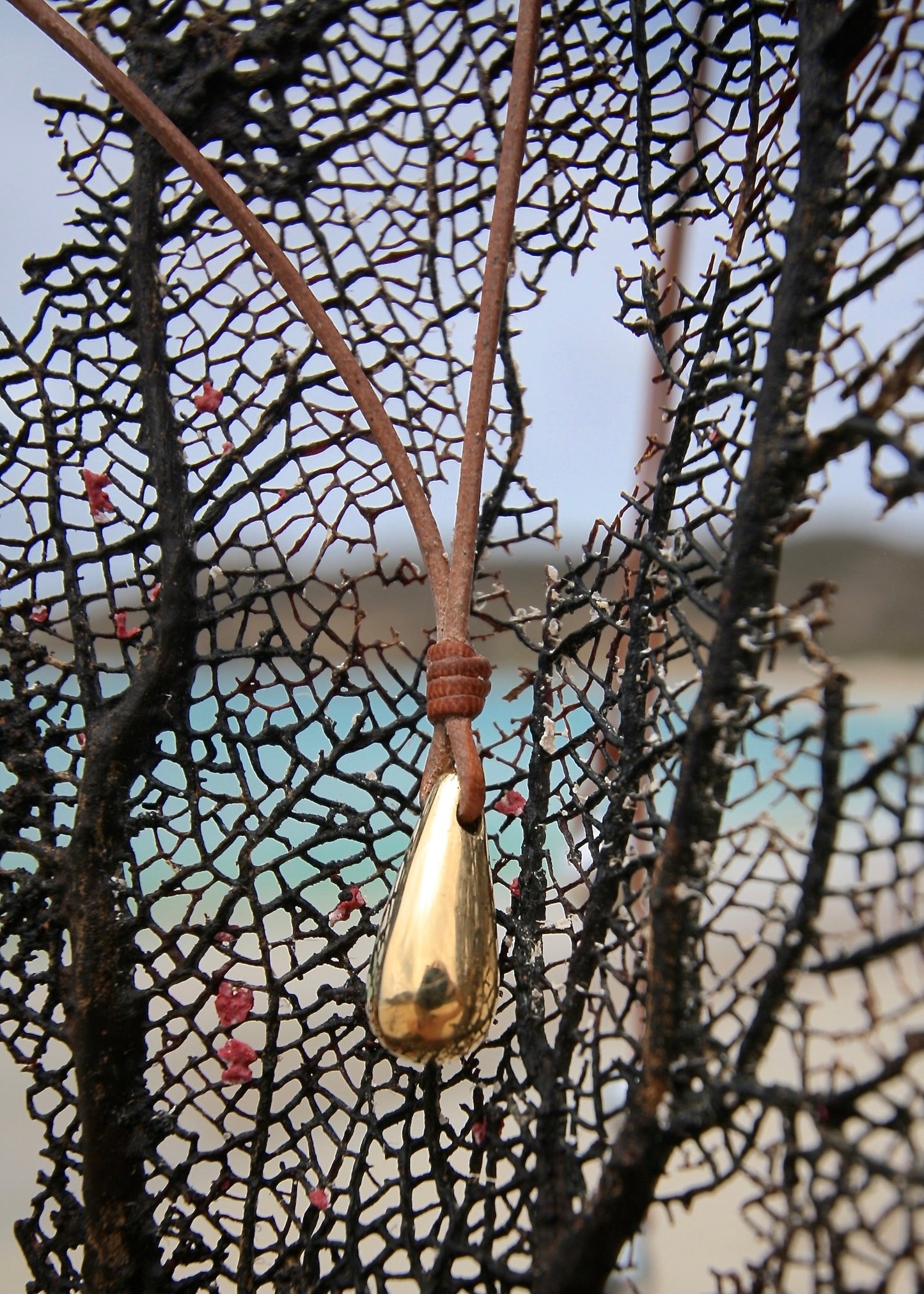 Solid gold teardrop pendant leather necklace on sea net, Caribbean turquoise sea