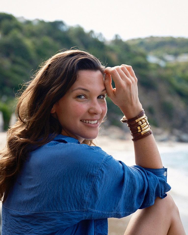 Smiling woman on the beach wearing a kangaroo leather and gold bead bracelet