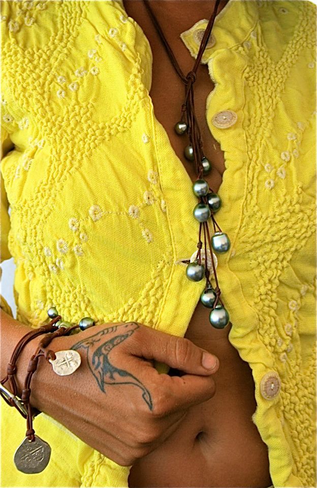 Tahitian pearl tassel necklace over a yellow embroidered top, leather coin bracelet