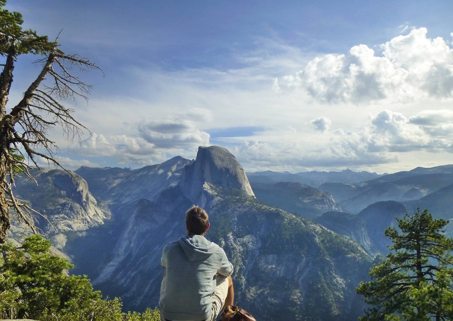 Ted Deltour sitting on a clifftop overlooking mountain peaks and valley