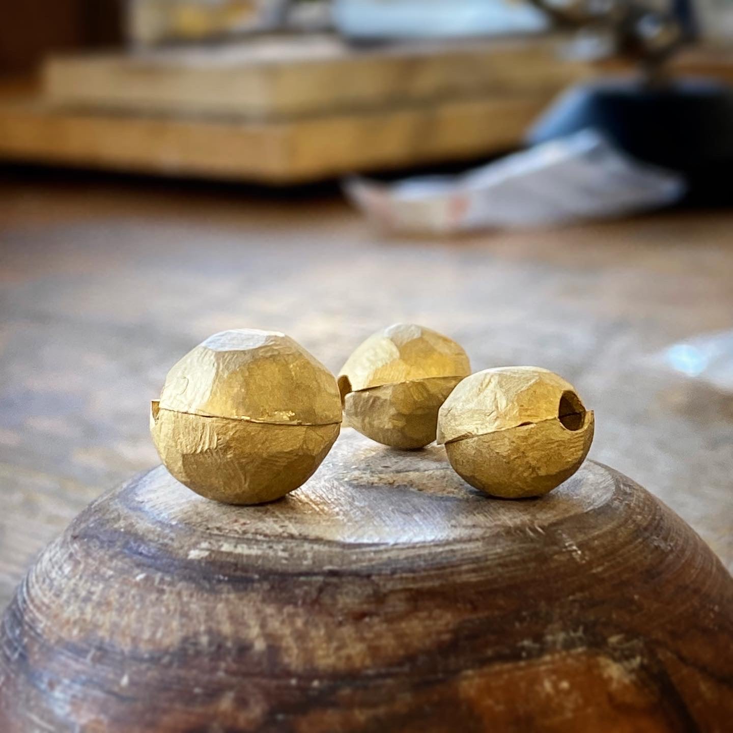Hand-sculpted raw gold sphere beads on wooden block, workshop in progress