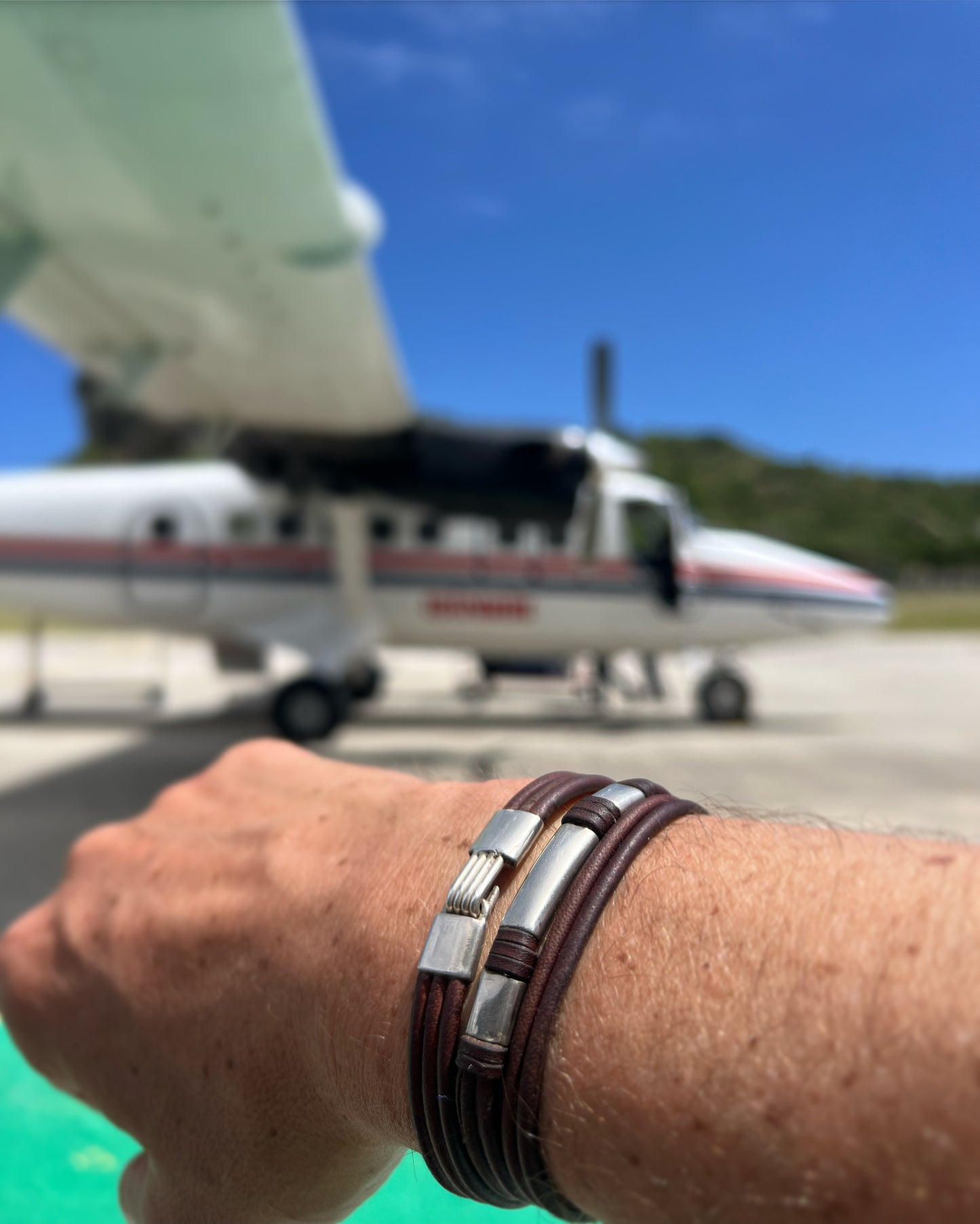 Wrist with kangaroo leather and silver bracelet, boarding a St Barth flight
