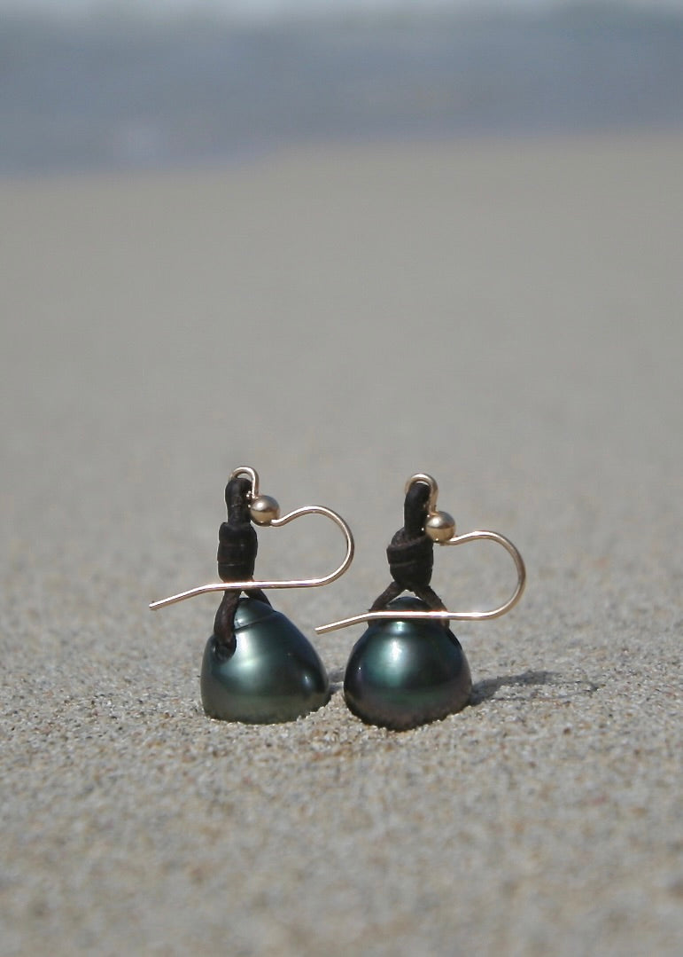 Dark Tahitian pearl leather earrings on sand, Caribbean beach