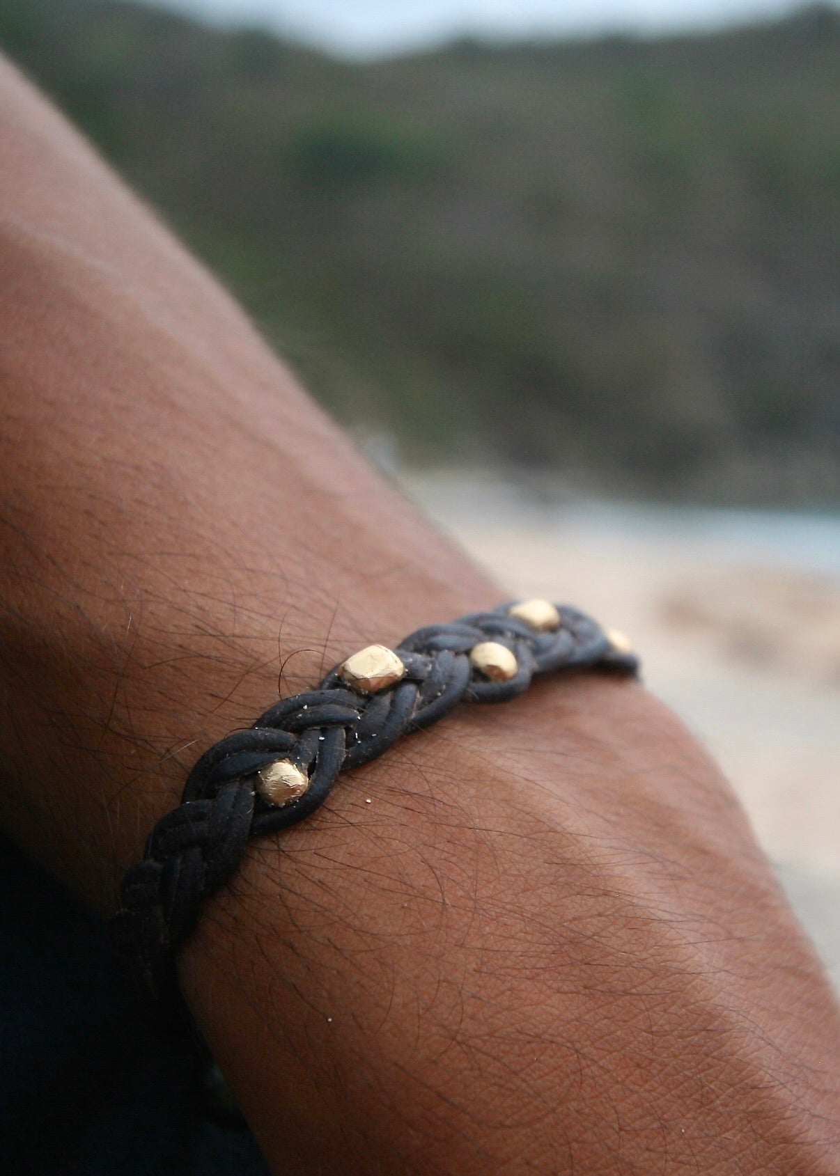 Braided leather and 18K gold bead bracelet worn on wrist, St Barth beach