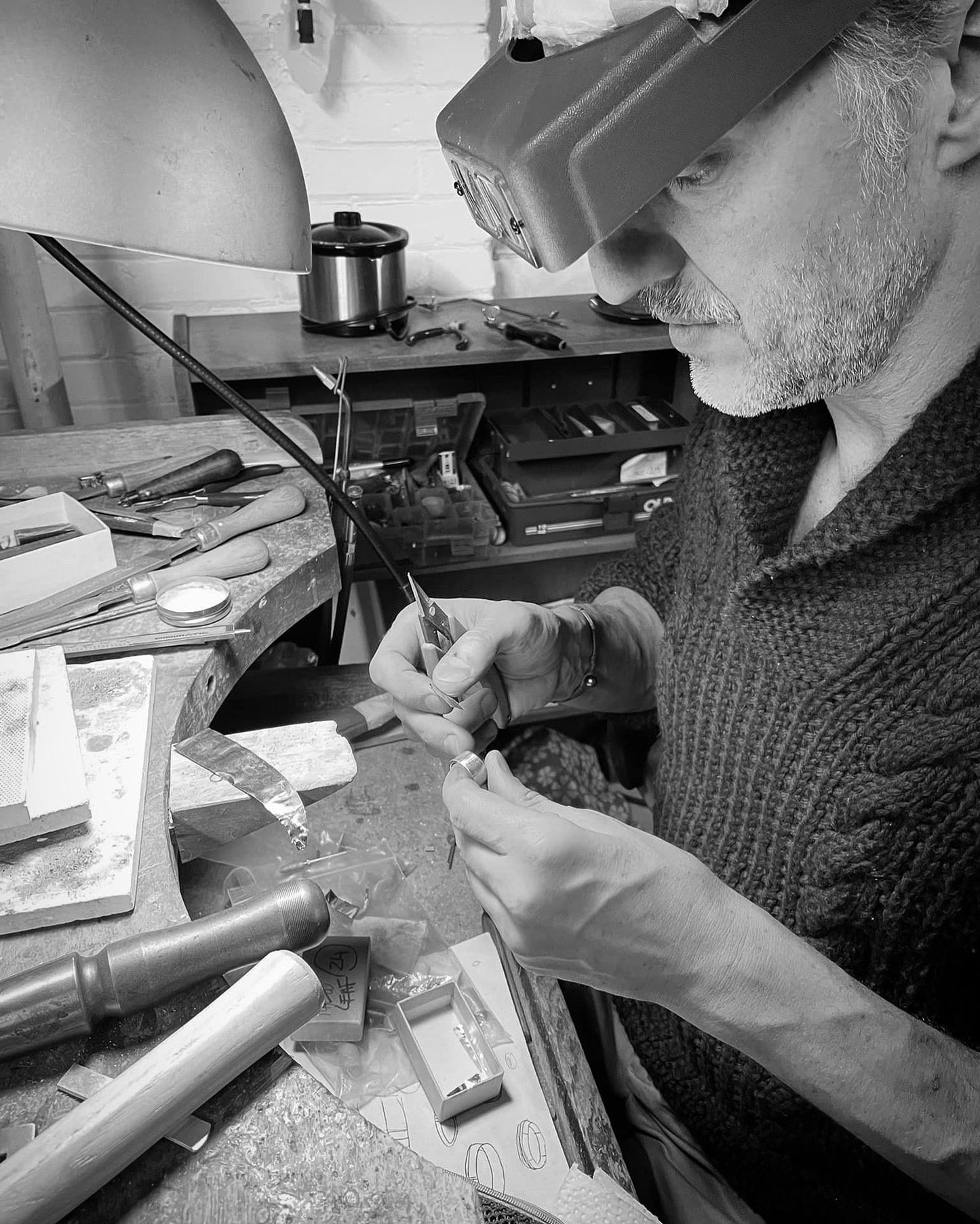 Ted Deltour engraving jewelry at workbench, black and white workshop portrait
