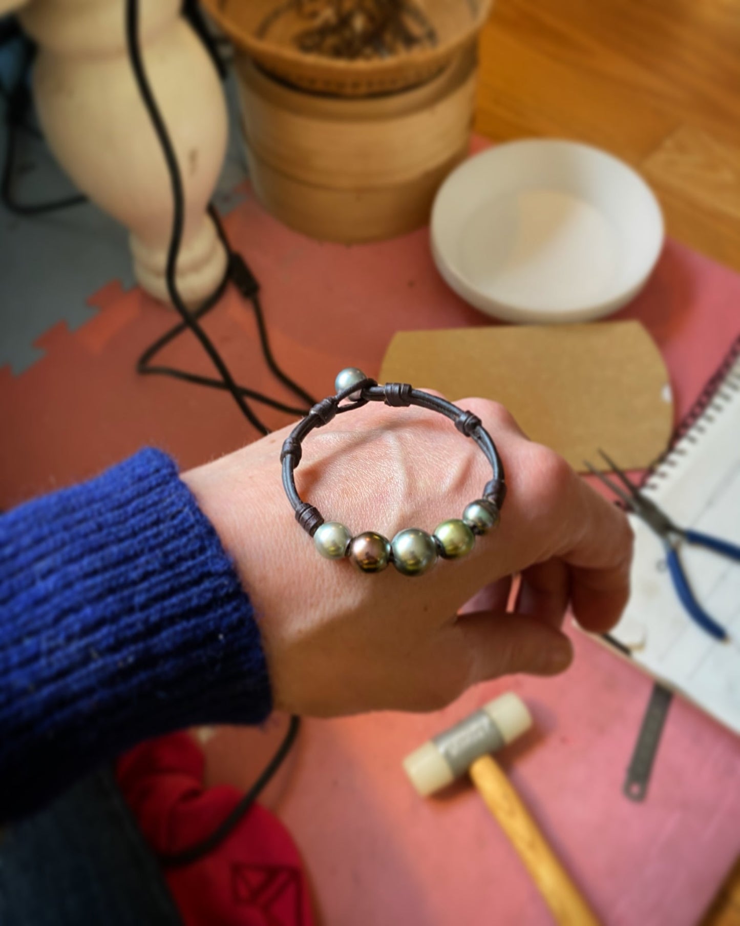 Tahitian pearl leather bracelet being knotted by hand, jewelry workshop