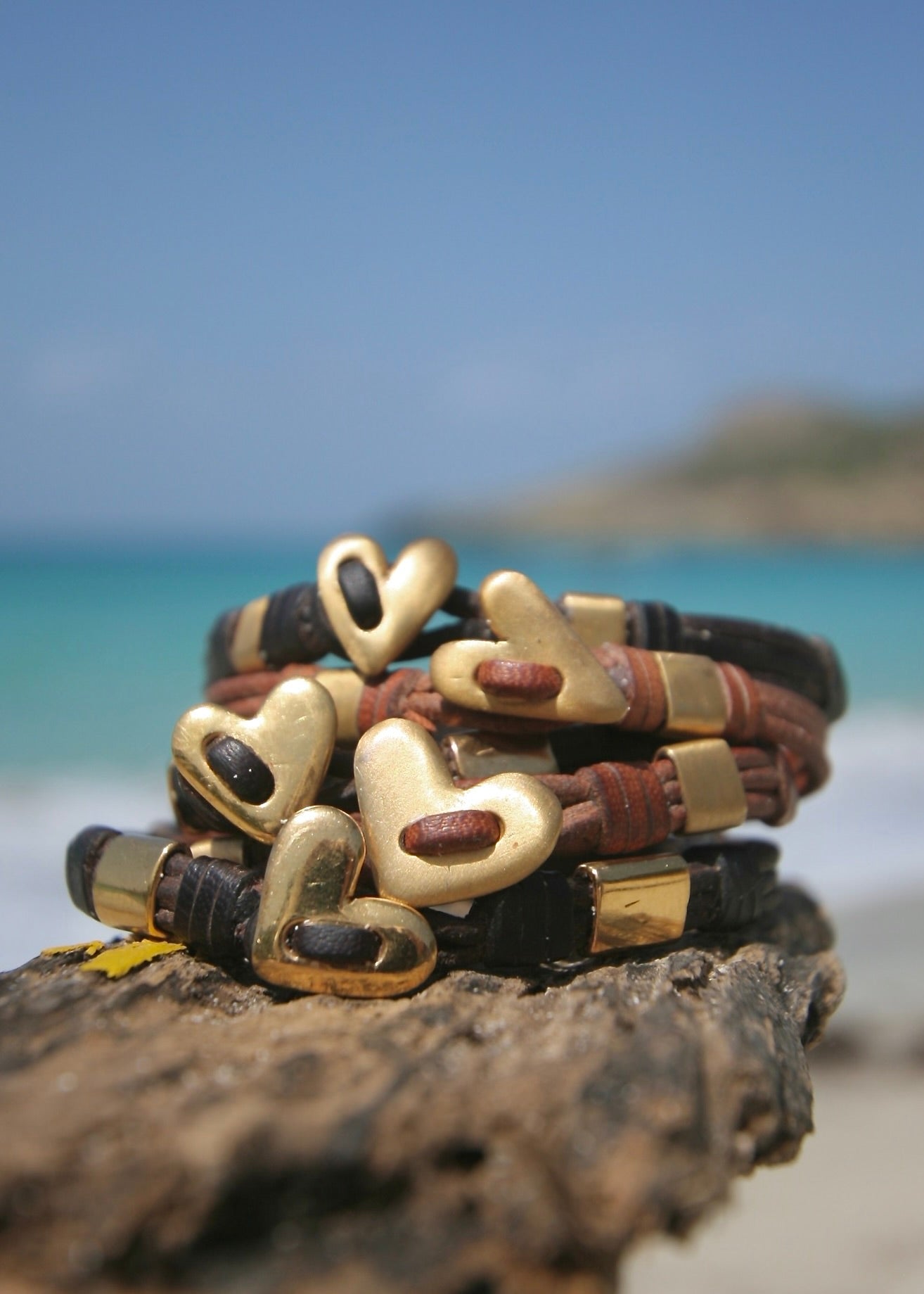 Handmade 18K gold heart bracelet stack on driftwood, St Barth beach