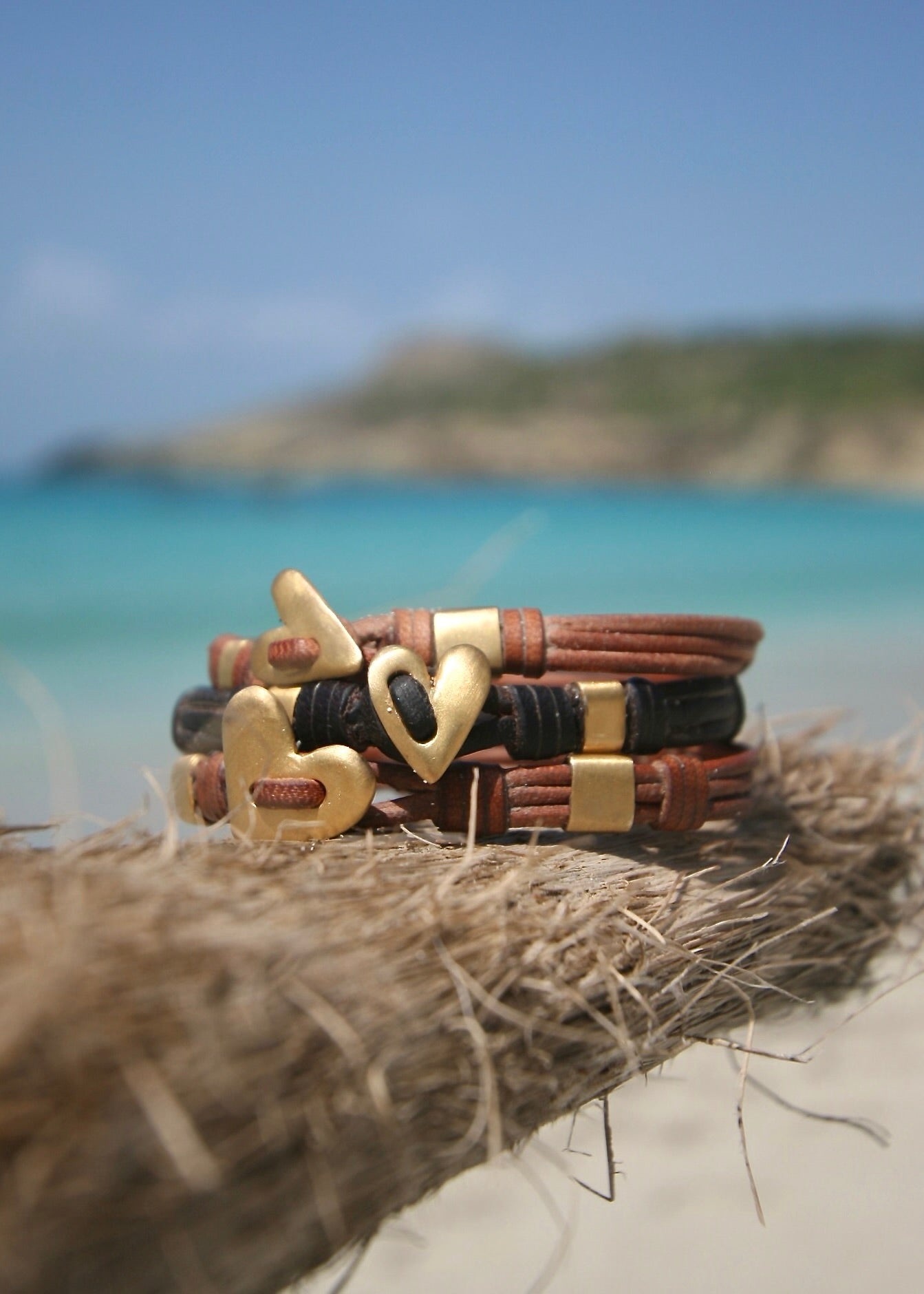 Trésors de St Barth gold heart leather bracelets on driftwood, Caribbean sea

