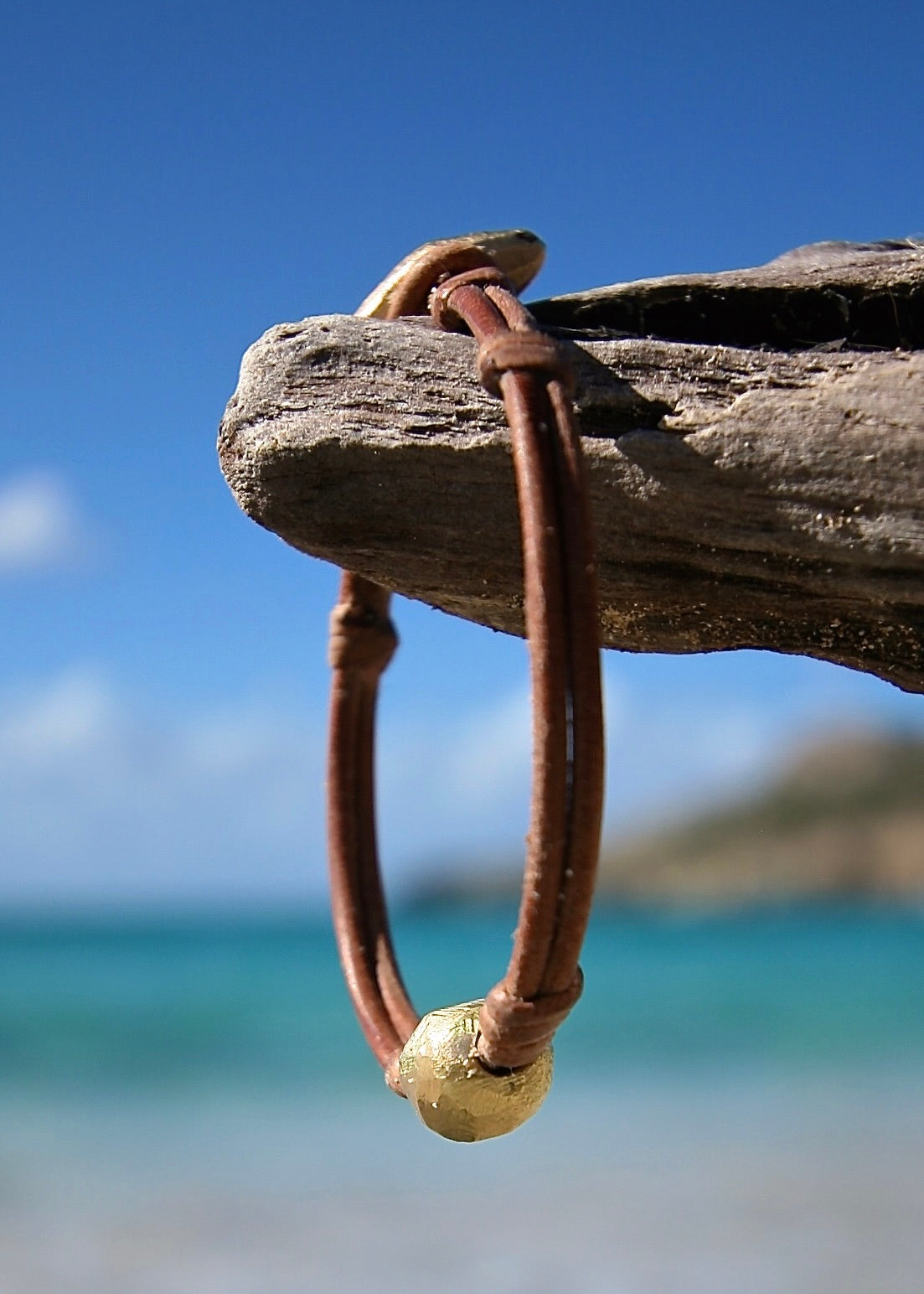 Handmade gold bead leather bracelet on driftwood, Caribbean turquoise sea