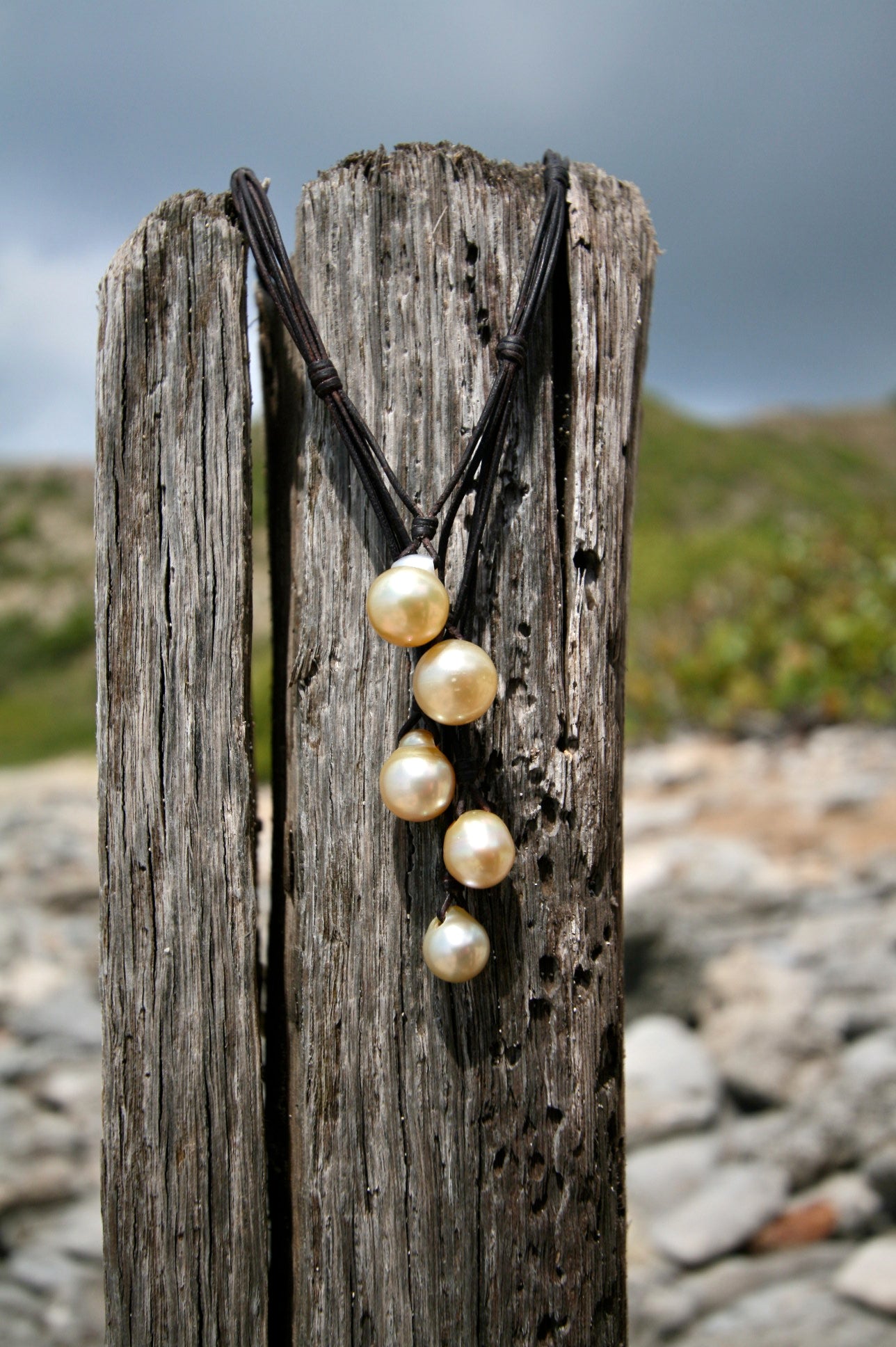 Graduated pearl drop necklace hanging from a weathered wooden post