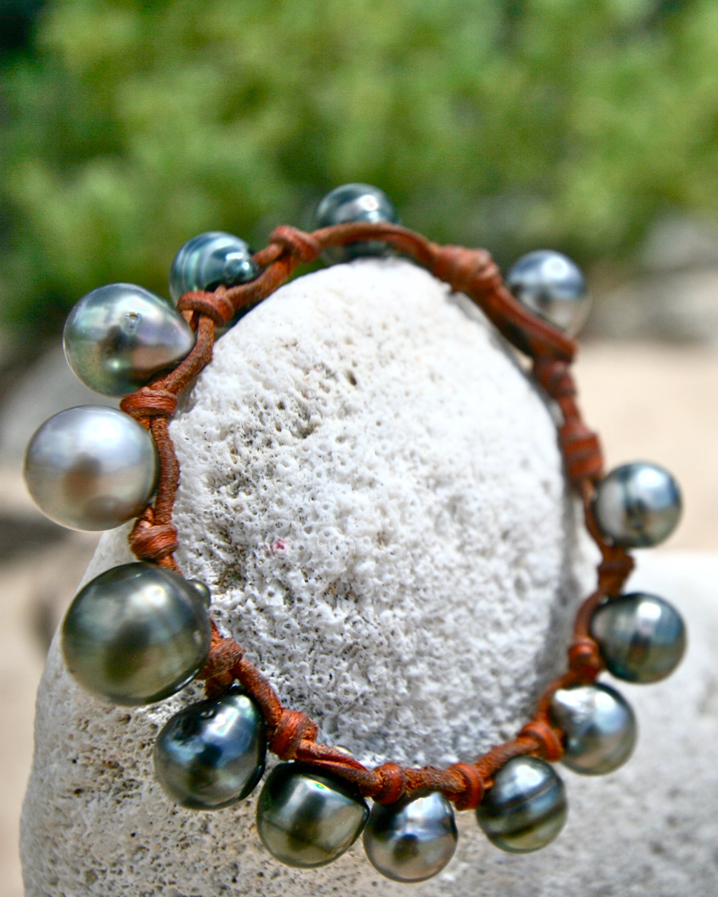 Tahitian pearl bracelet wrapped around a white coral stone, leather knots