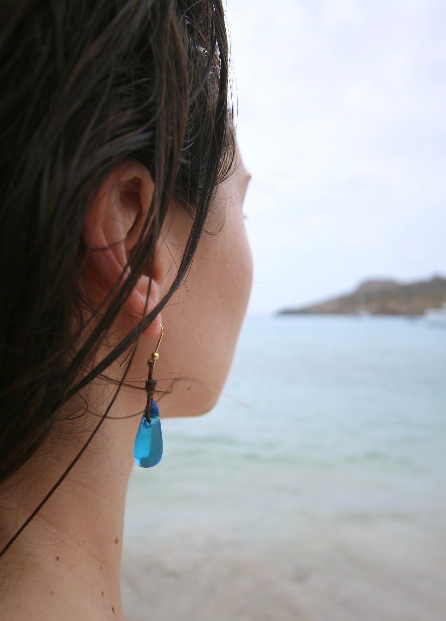 Woman by the water wearing a blue sea glass drop earring