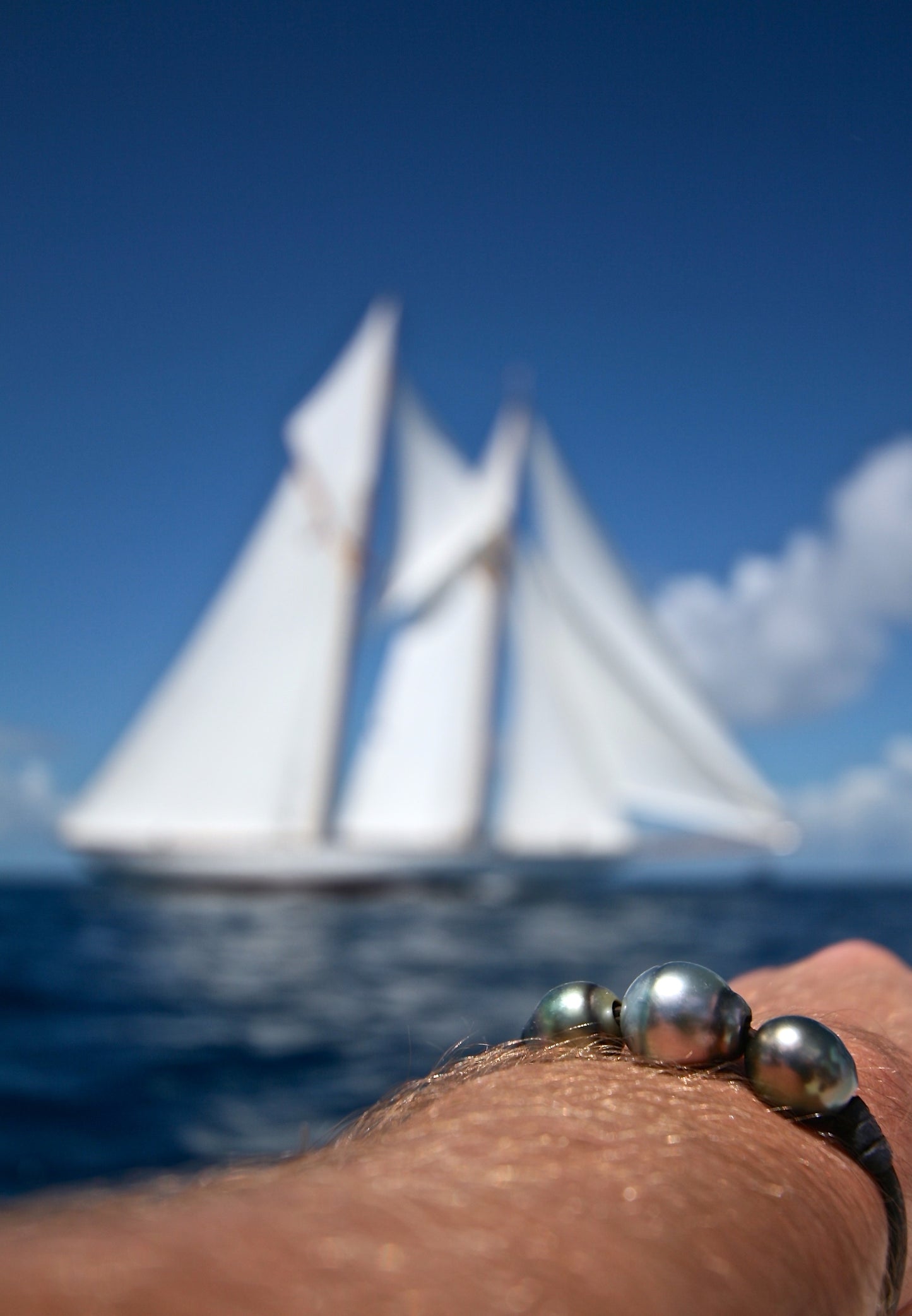 Tahitian pearl bracelet on wrist, sailing schooner in the background