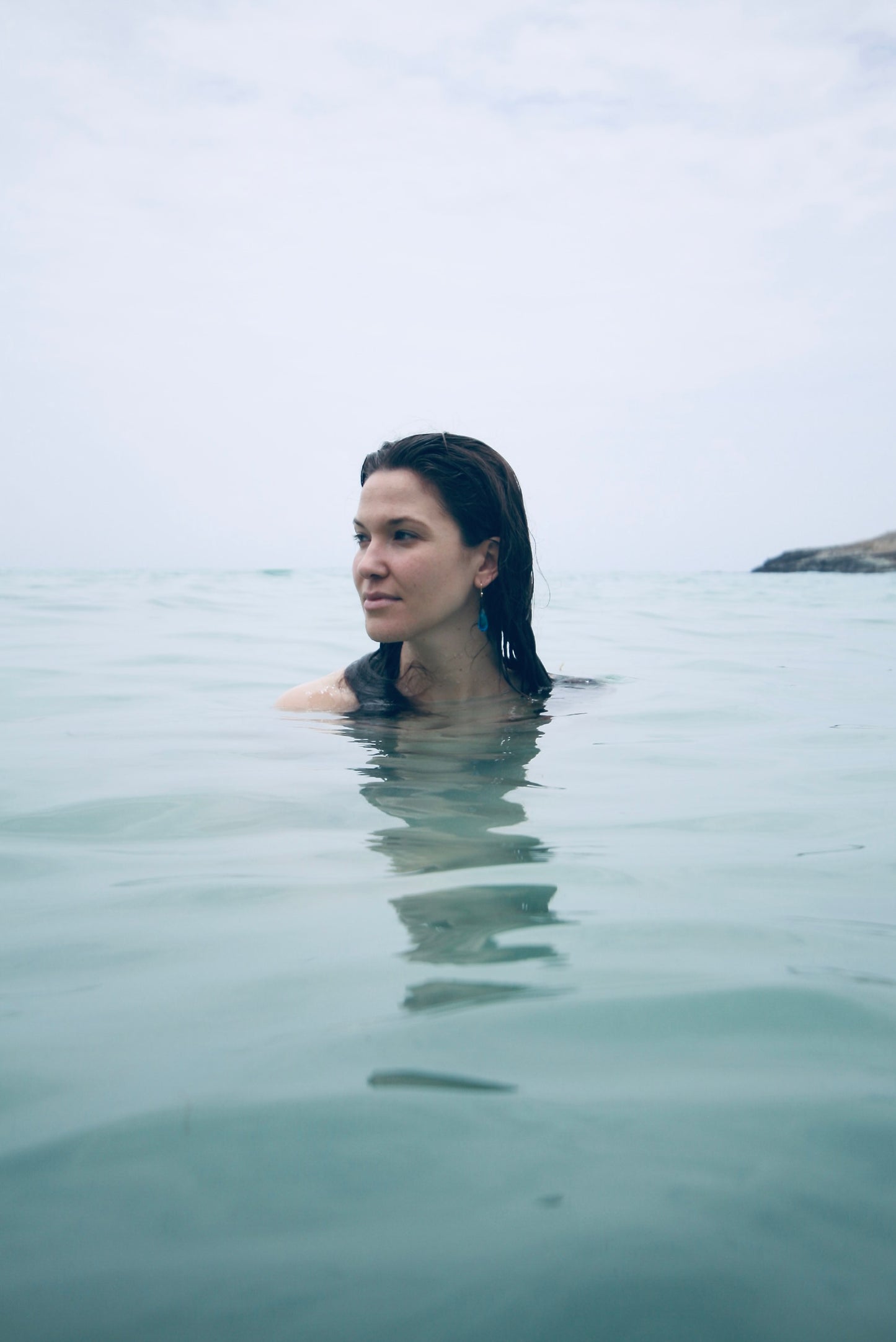 Woman wading into calm turquoise waters off Saint-Barthélemy wearing earrings