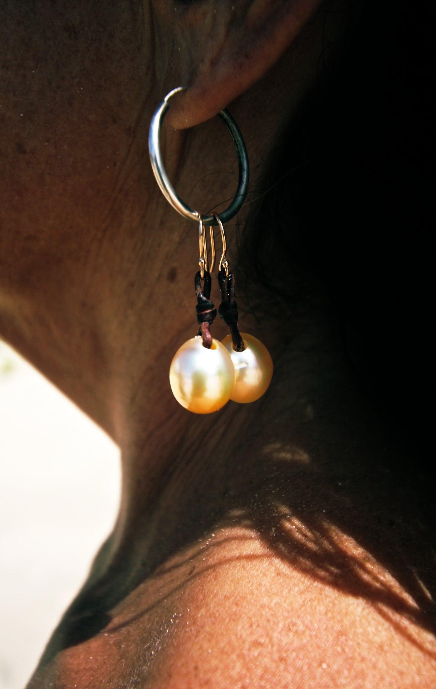 Golden South Sea pearl drop earrings on leather, close-up detail