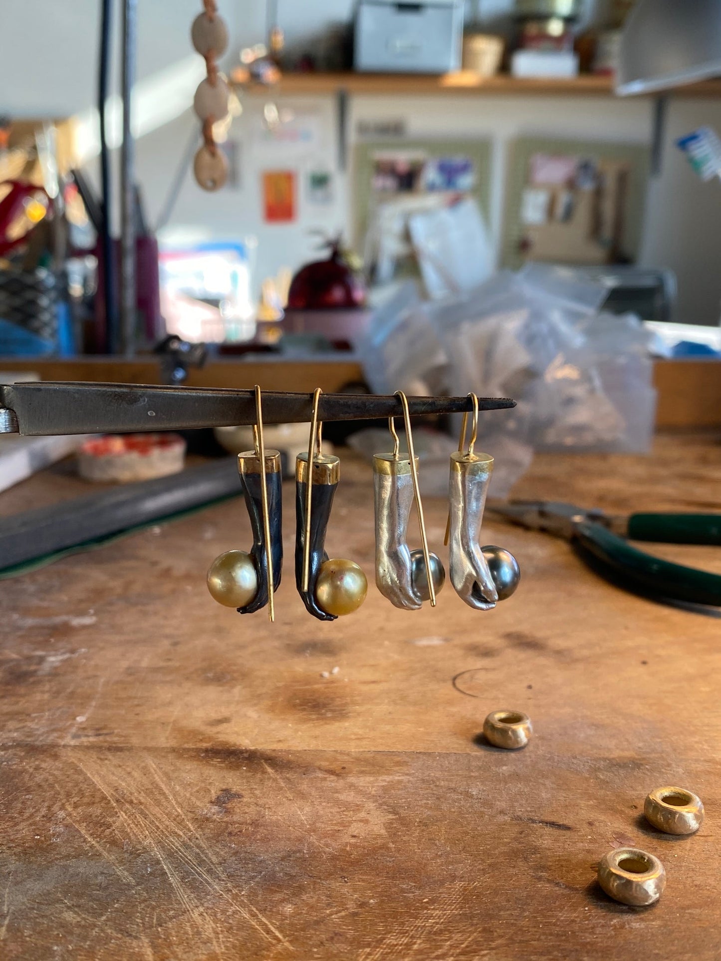 Handmade gold drop earrings in progress on workbench, jewelry atelier