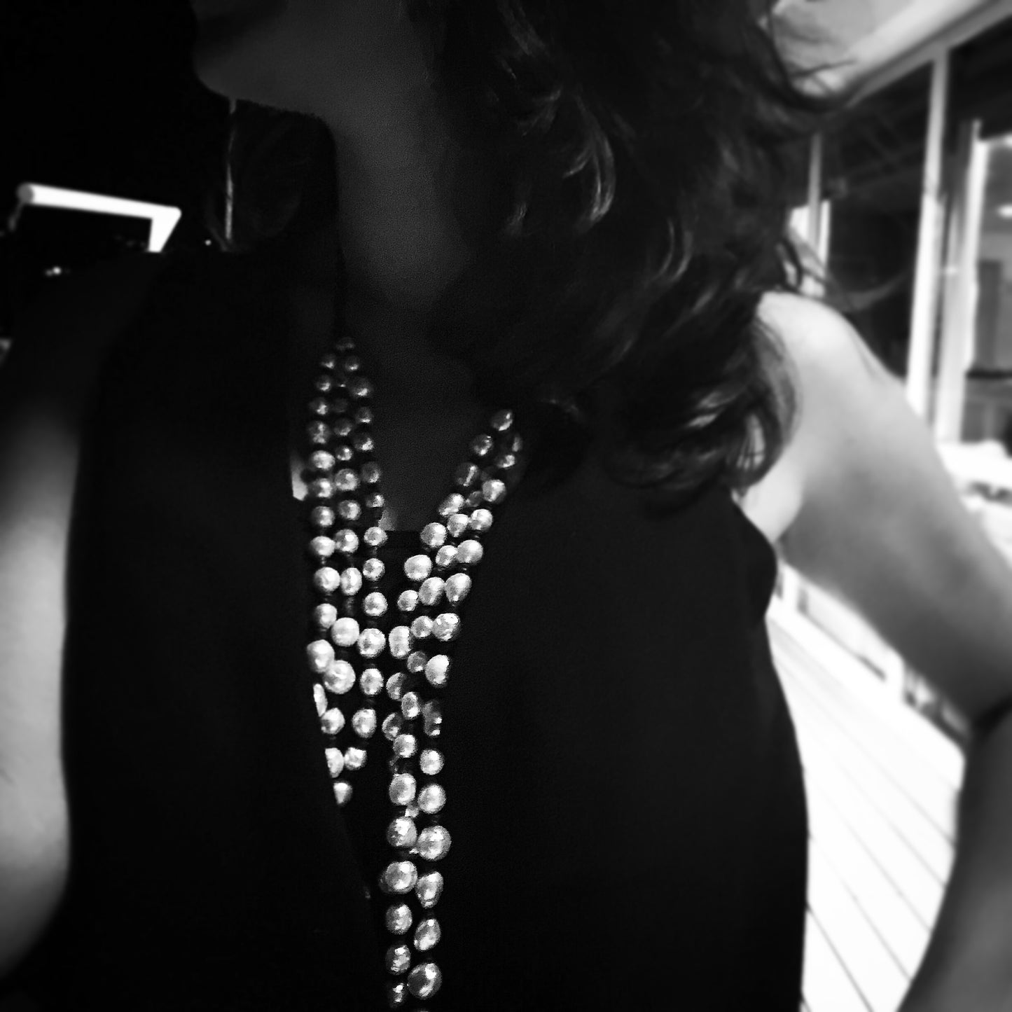 Black and white portrait, layered silver pearl necklaces on little black dress