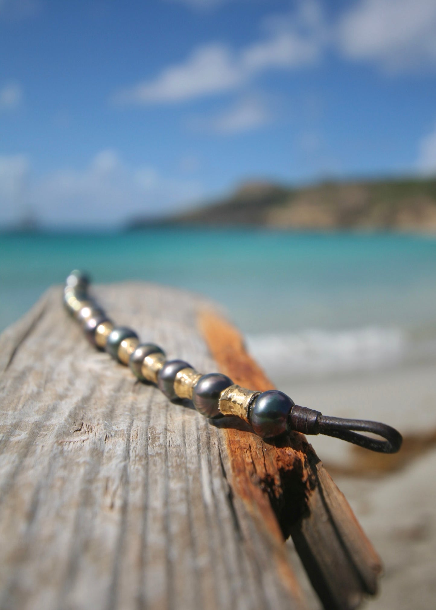 Close-up of Tahitian pearl clasp and kangaroo leather loop on black pearl and gold bead bracelet — handcrafted luxury boho bracelet from St. Barth.