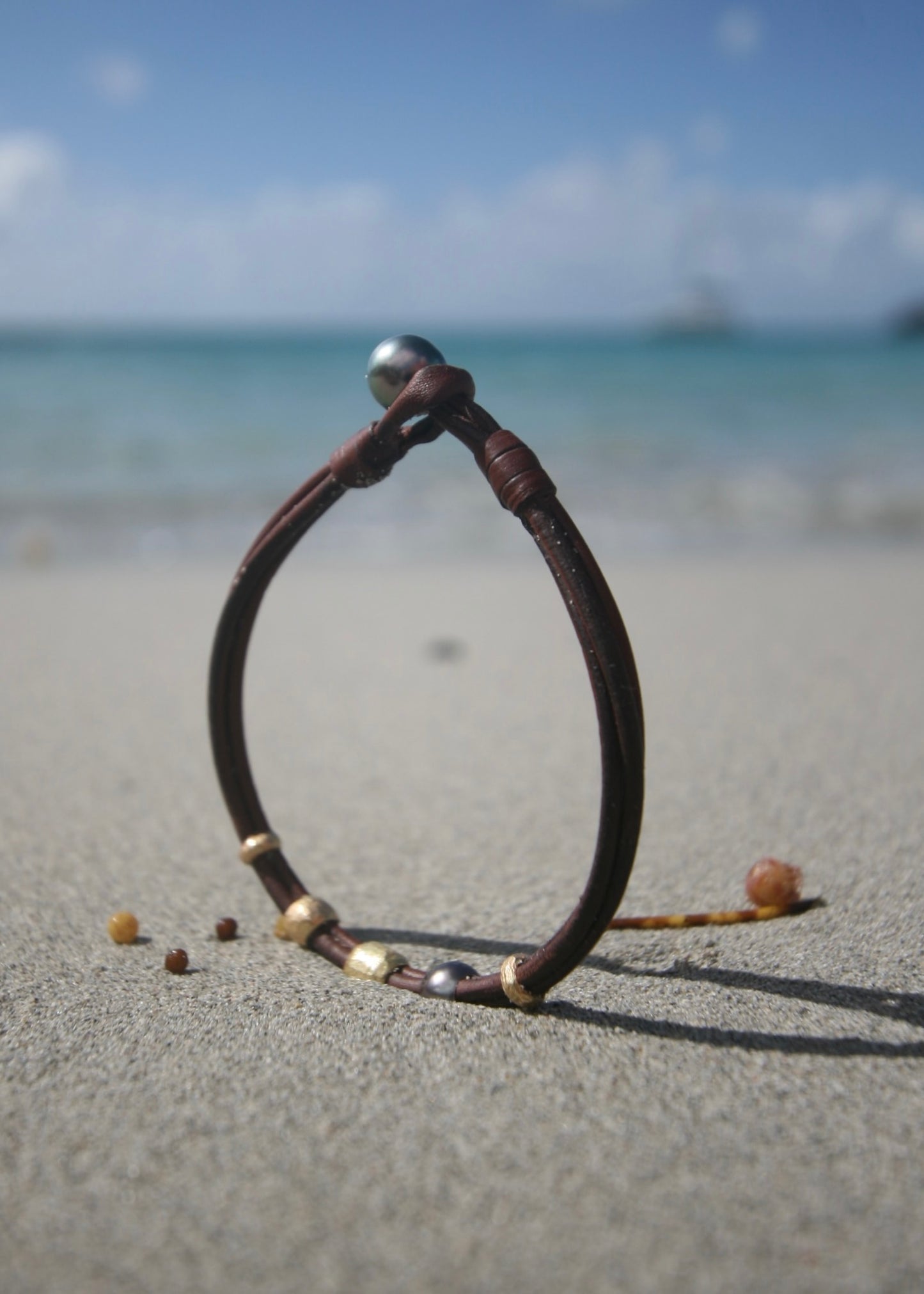 Minimalist 18K gold and Tahitian pearl leather bracelet on St Barth beach sand