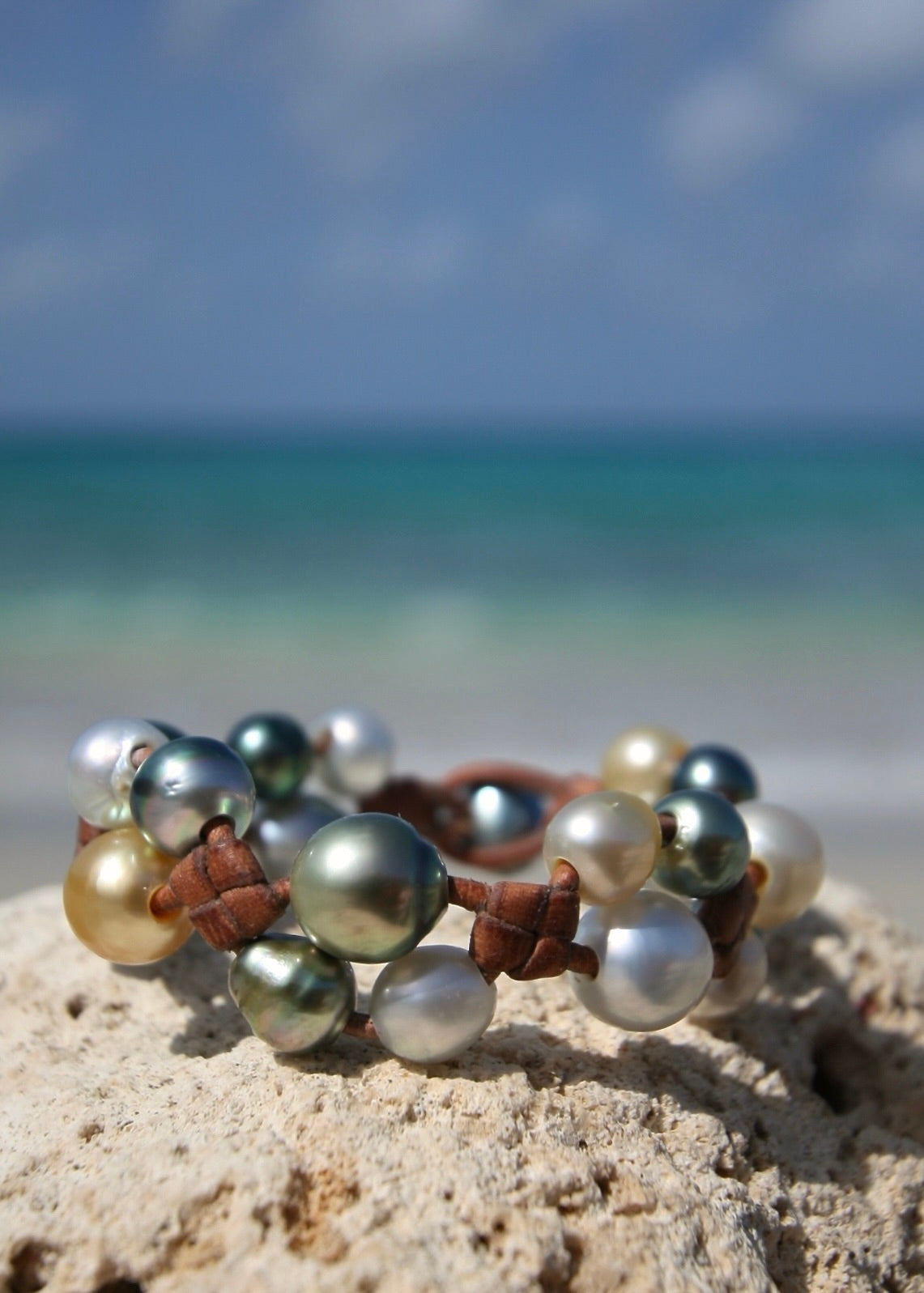 Multicolor pearl cluster leather bracelet on sand, Caribbean turquoise sea