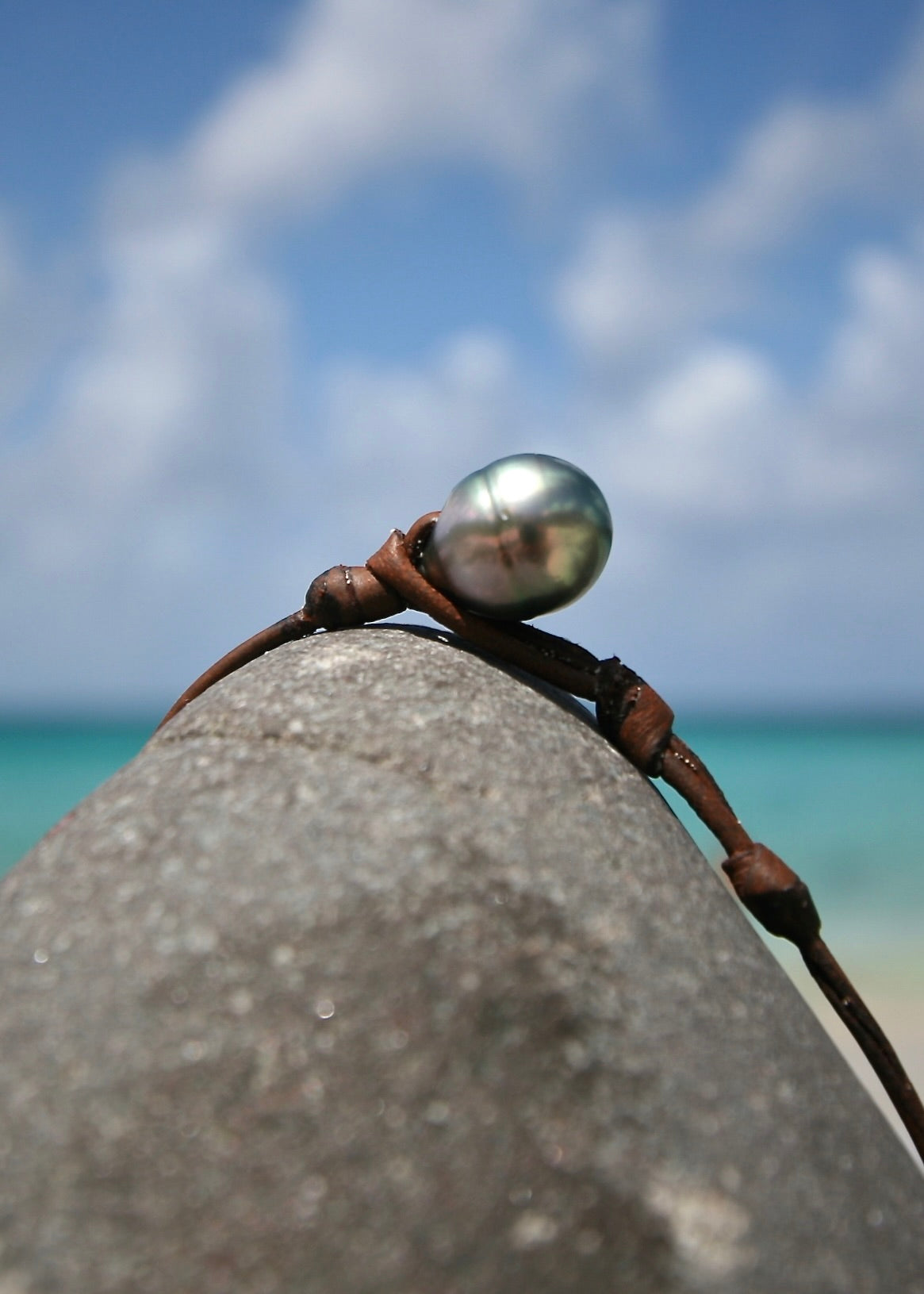 Single Tahitian pearl leather cord close-up on rock, Caribbean sea
