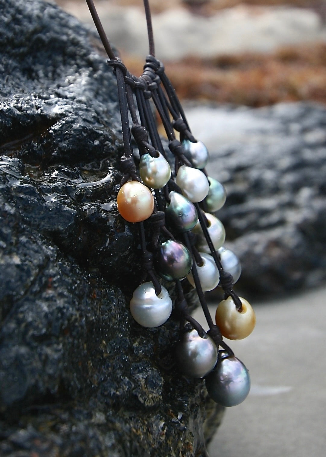 Multicolor pearl cascade necklace on dark rock, St Barth coastline