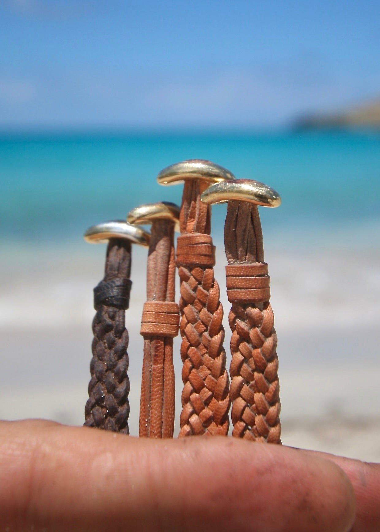 Handmade crystal sea glass leather bracelets held in hand, Caribbean sea
