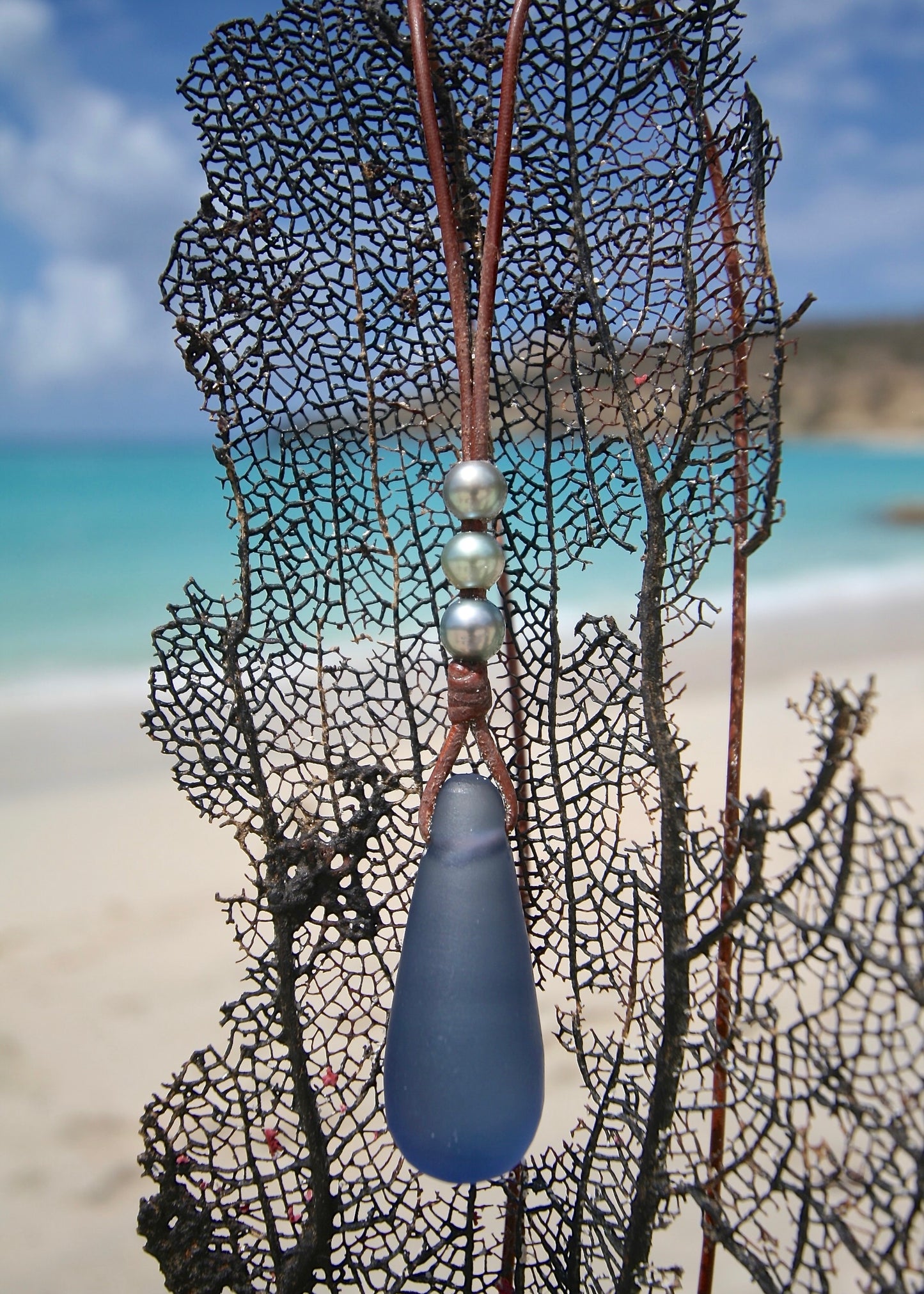 Handmade crystal glass pendant pearl necklace on sea net, Caribbean turquoise sea
