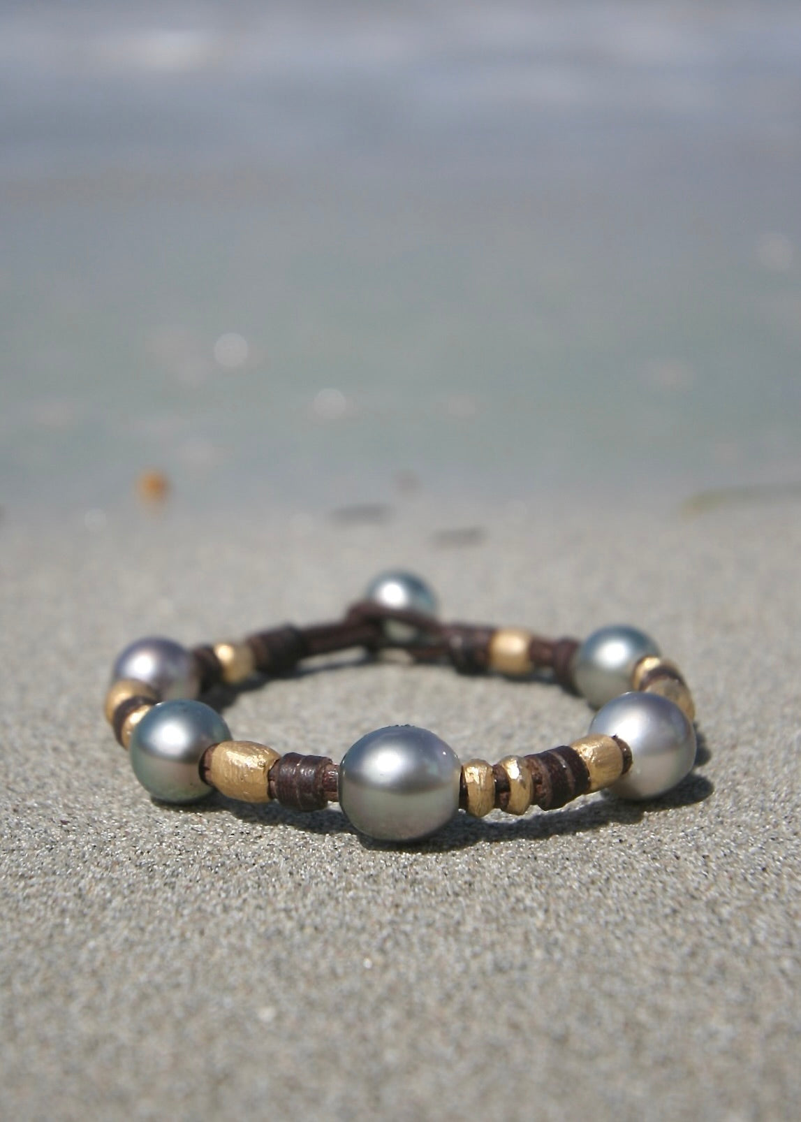 Trésors de St Barth Tahitian pearl gold bracelet on sand, Caribbean turquoise sea