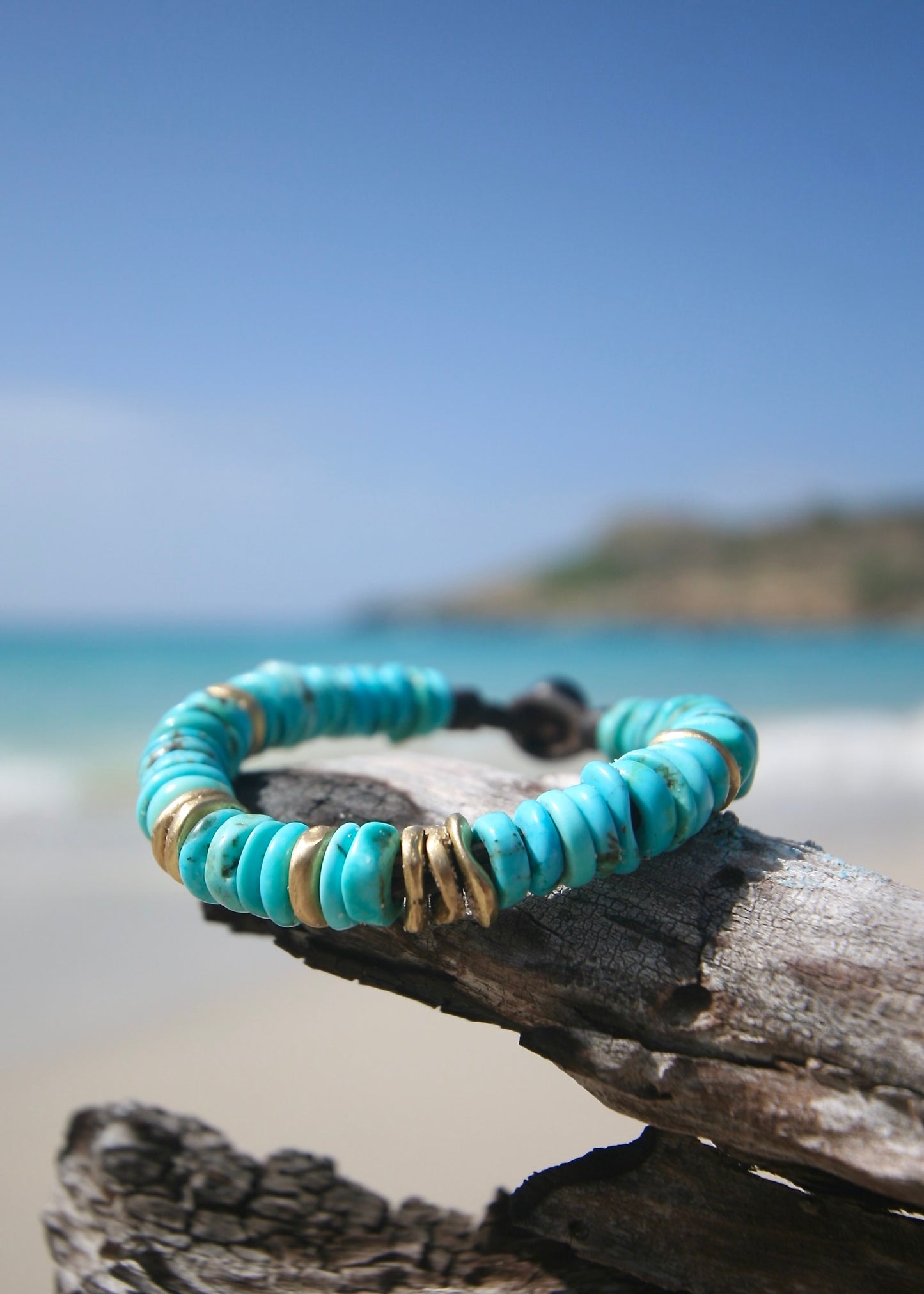 American turquoise bracelet with eight 18K gold beads and Tahitian pearl clasp on leather on beach wood