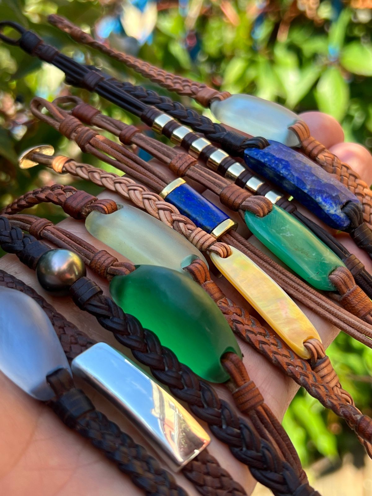 Braided leather bracelets with polished sea glass stones held in hand, one of a kind jewelry St Barth