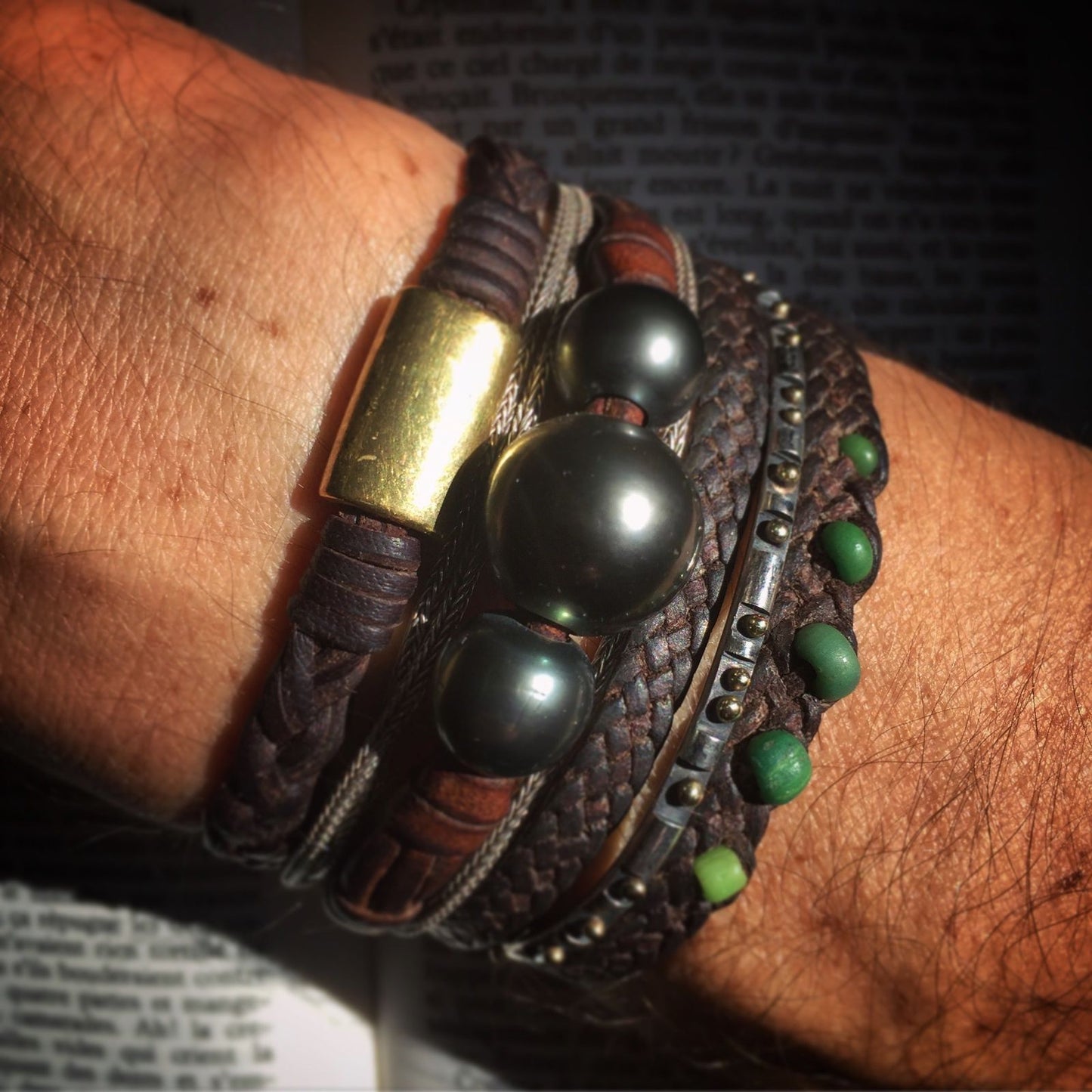 Stacked leather cuff bracelets with black pearl beads, brass and malachite accents worn on wrist, one of a kind jewelry St Barth