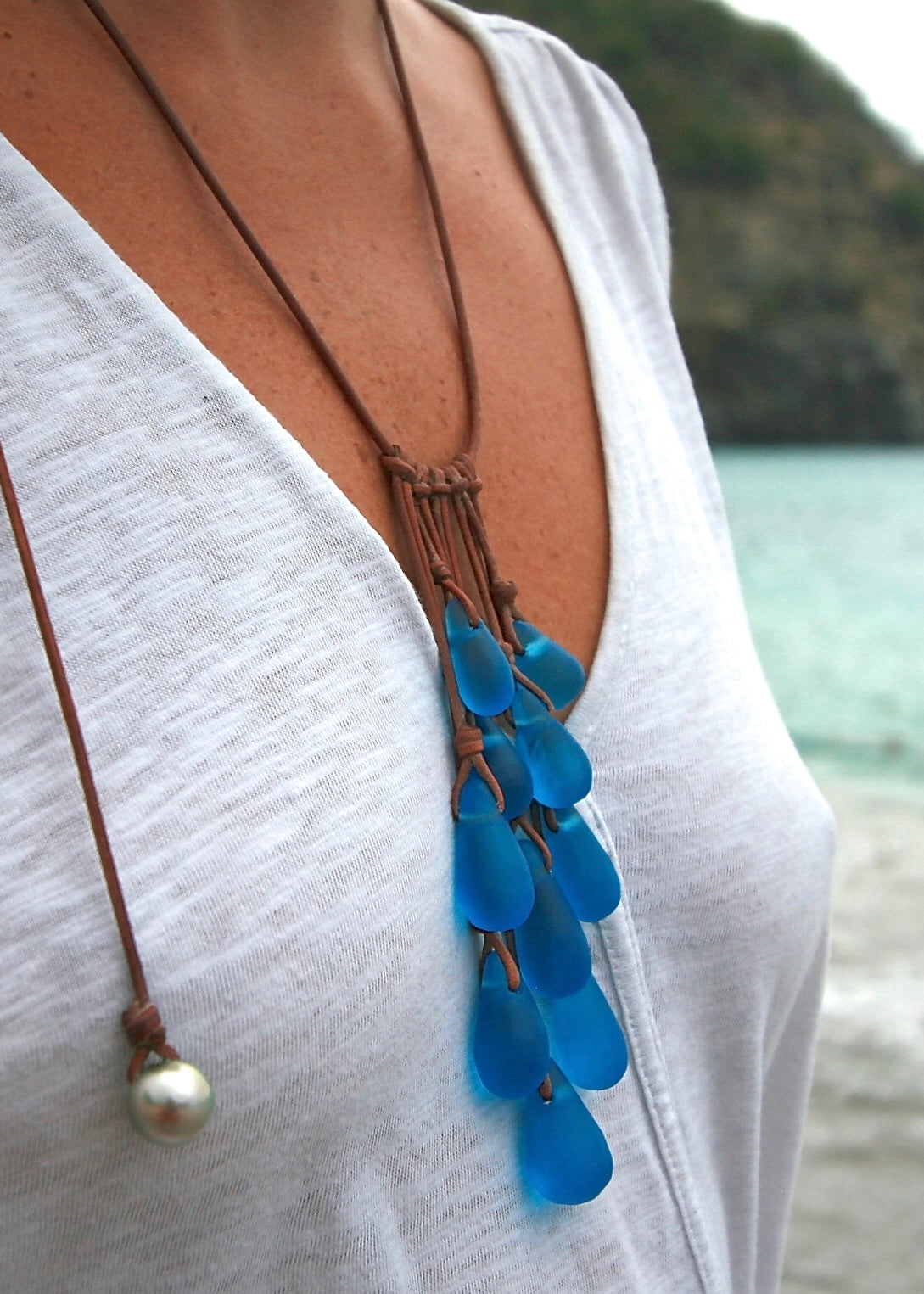 Crystal glass cascade necklace worn with white top showing adjustable leather sautoir with pearl clasp