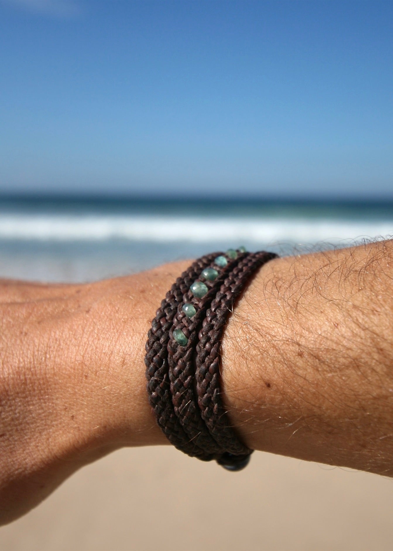 Genuine emerald and kangaroo leather triple wrap bracelet worn on man's wrist showing braided texture