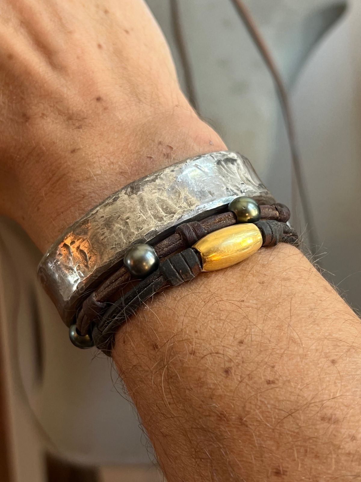 Hammered silver cuff bracelet stacked with pearl leather bracelets on wrist, one of a kind jewelry St Barth