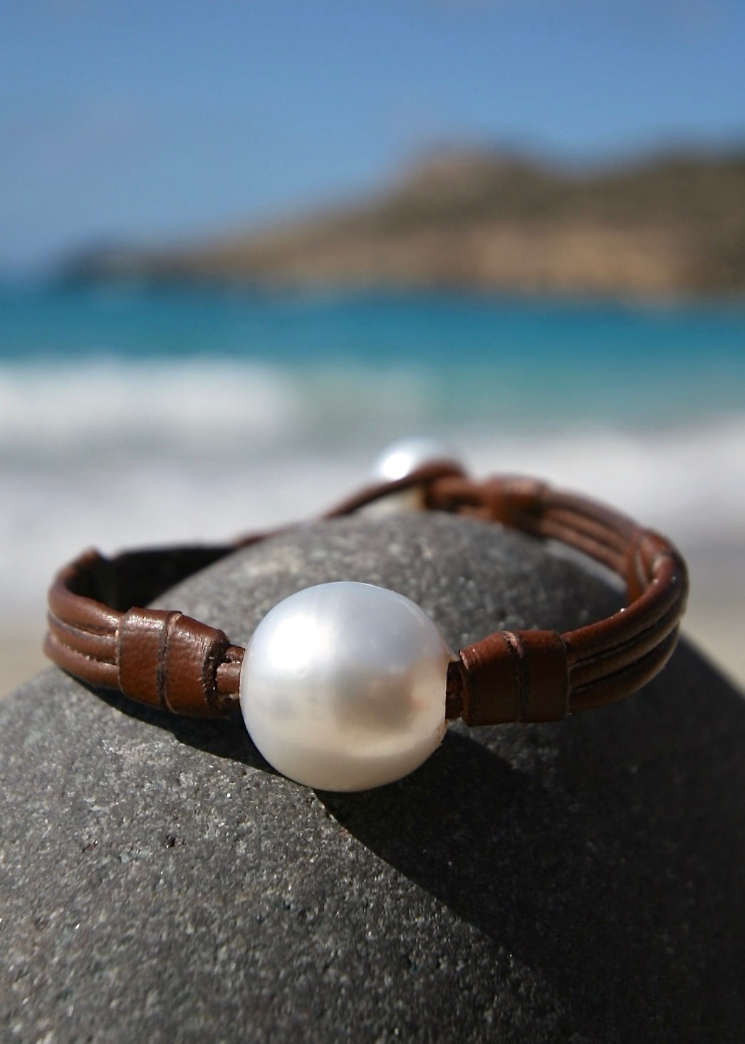 Large white Australian pearl leather bracelet on dark stone, St Barth beach