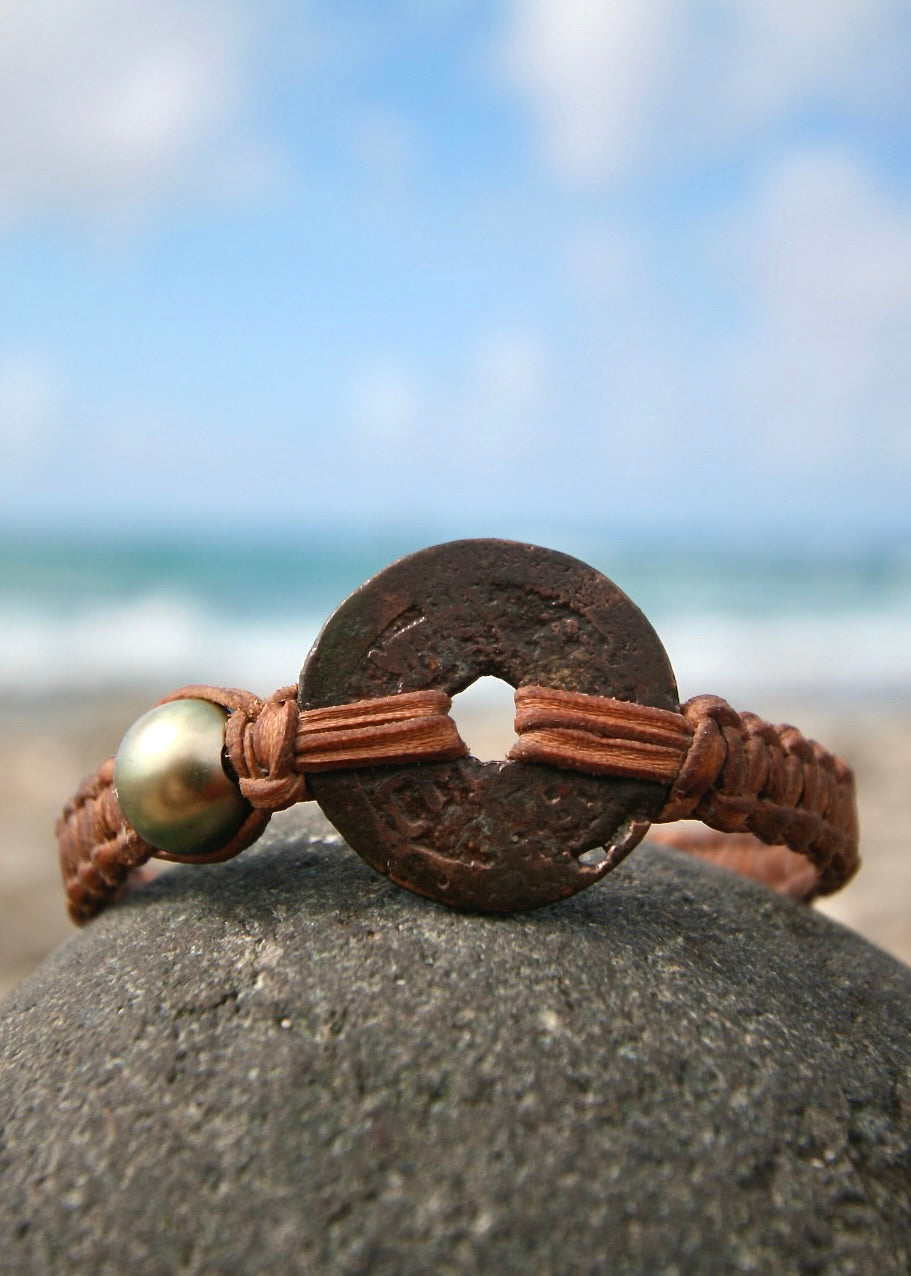 Trésors de St Barth authentic Japanese coin with center hole on braided leather bracelet with ocean behind