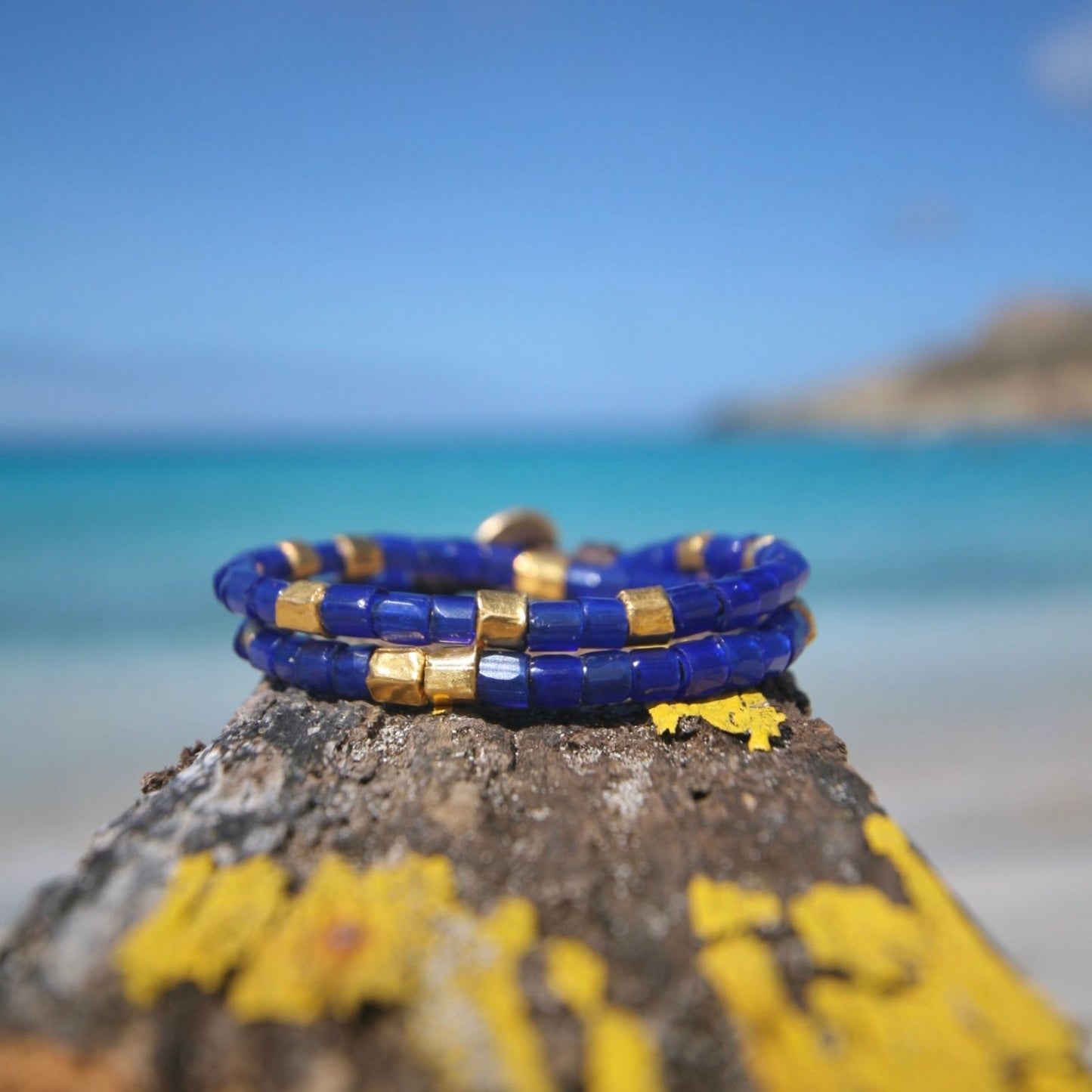 Stacked lapis lazuli bead bracelets with gold accents on beach rock, one of a kind jewelry St Barth