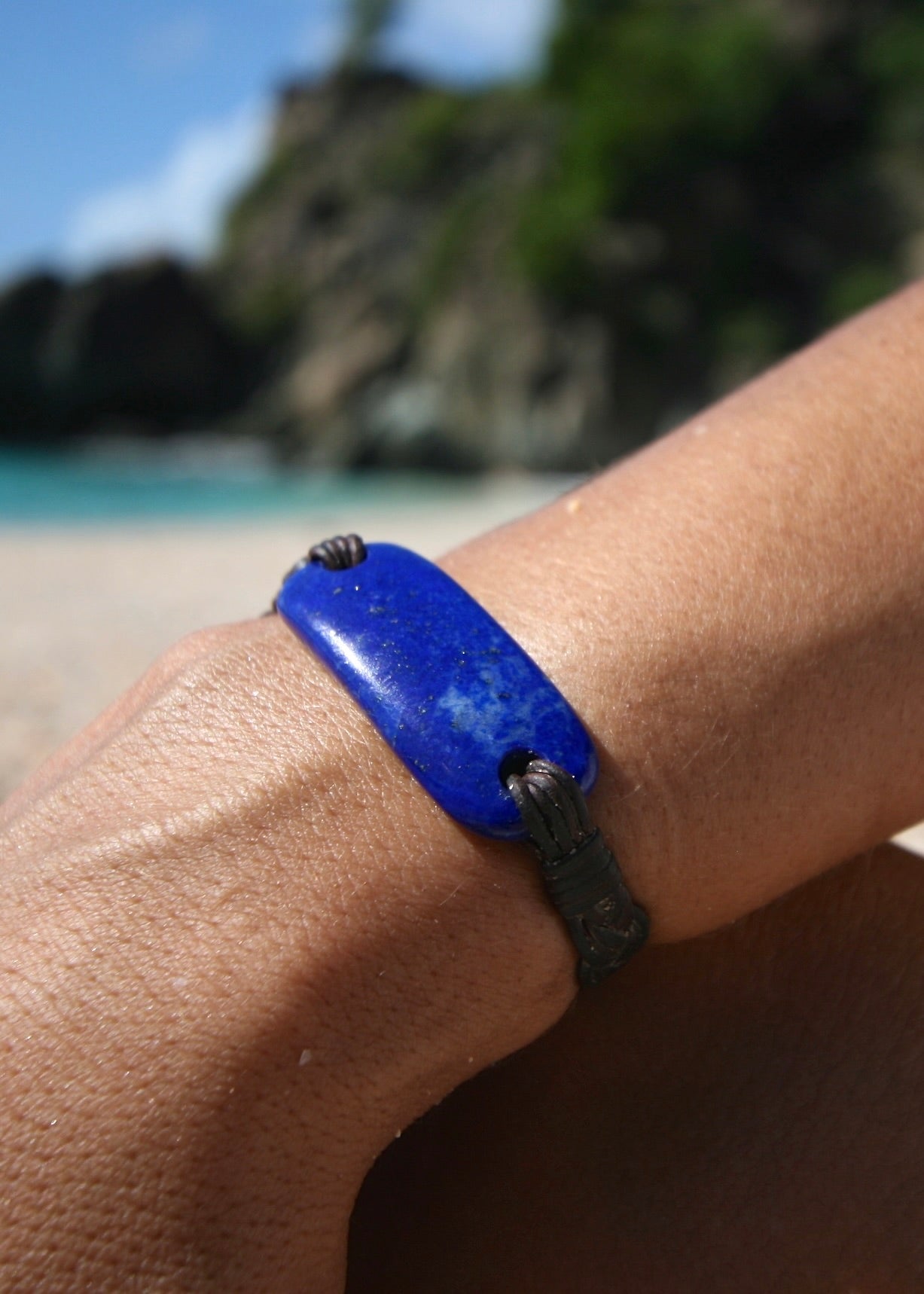 Trésors de St Barth lapis lazuli bracelet on braided kangaroo leather worn on wrist with Caribbean ocean
