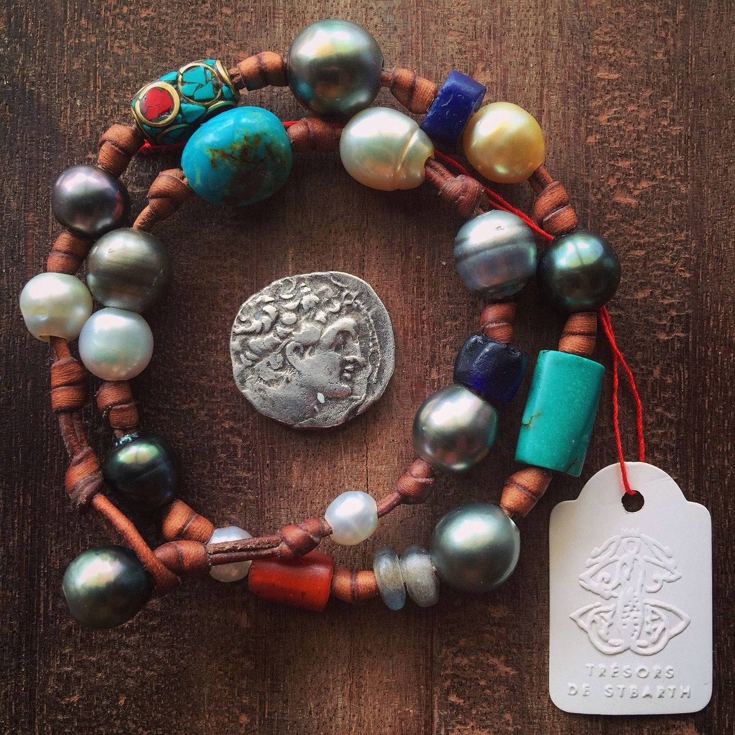 Pearl bracelet with ancient coin pendant and turquoise beads on wood surface, one of a kind jewelry St Barth