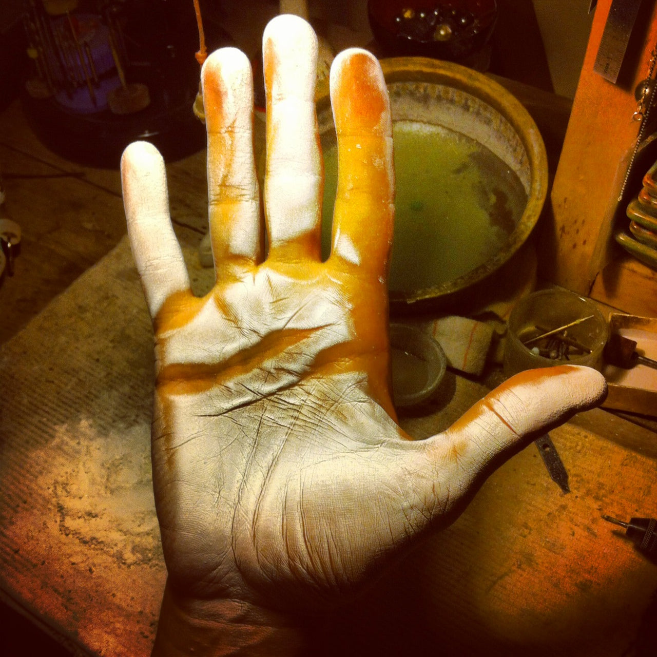 Jeweler's hand coated in cultured pearl dust, drilling process workshop
