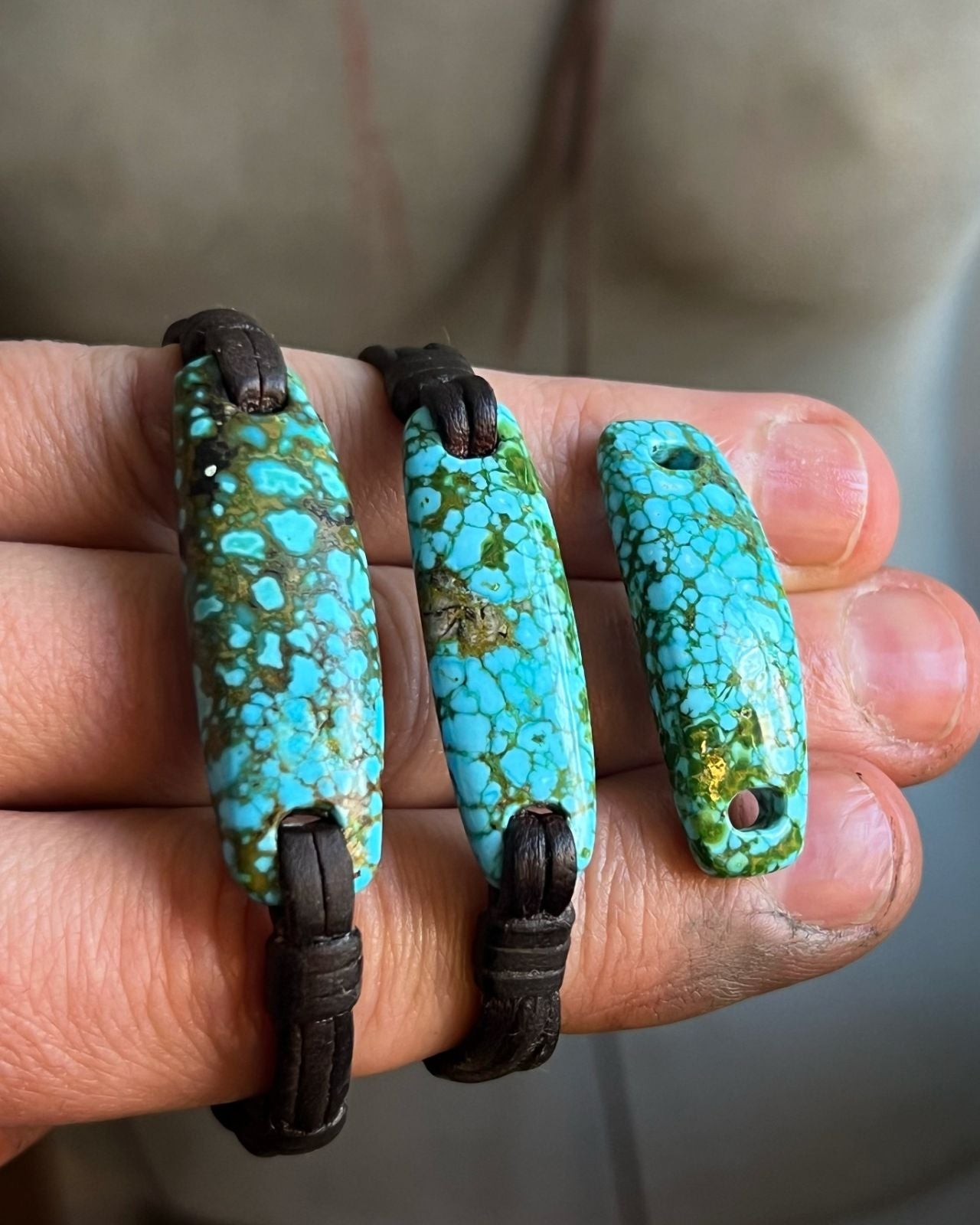 Raw turquoise stone slabs on leather bracelets held in hand, one of a kind jewelry St Barth