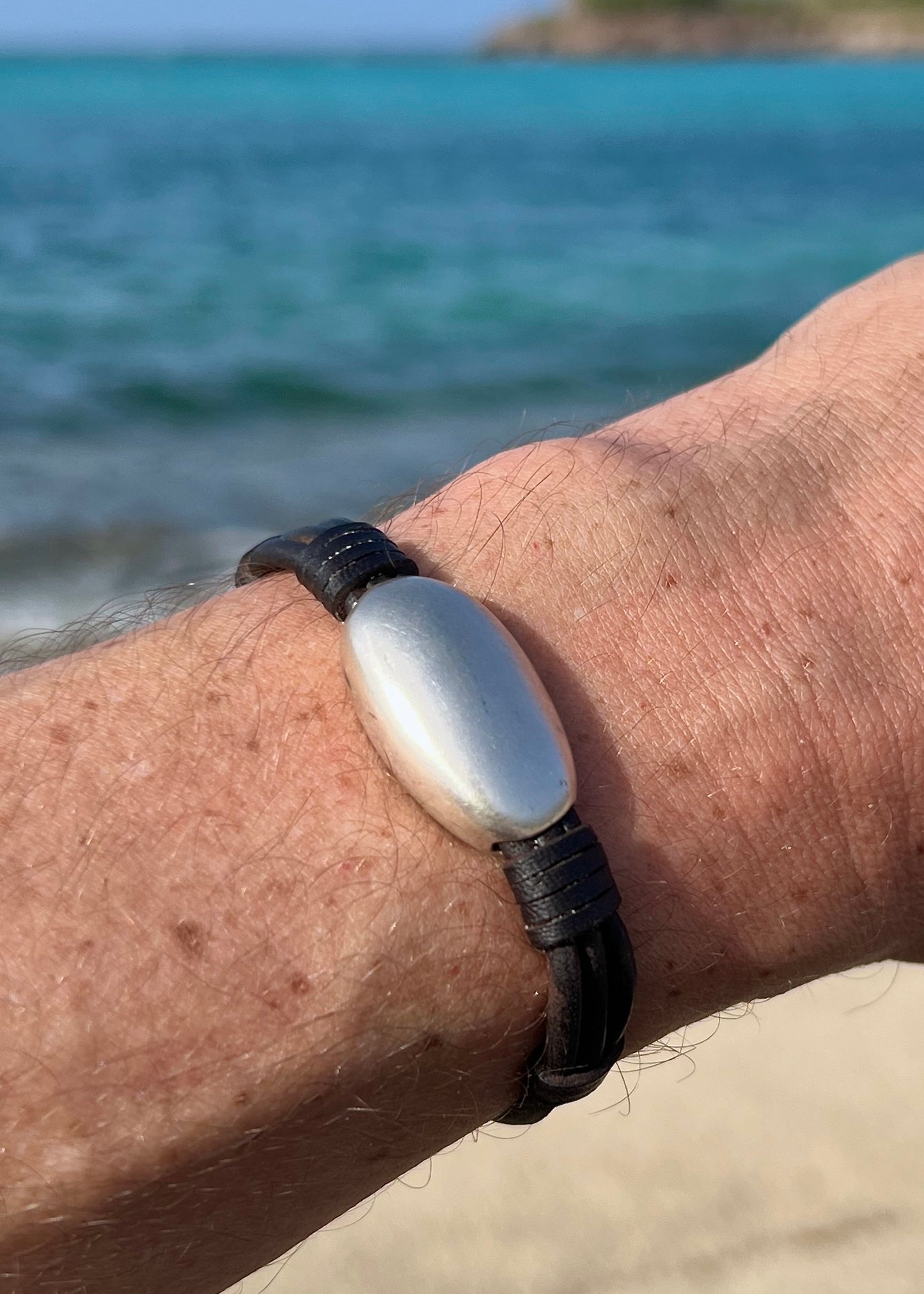 Sterling silver pebble bracelet on kangaroo leather worn on man's wrist showing organic sculpted shape