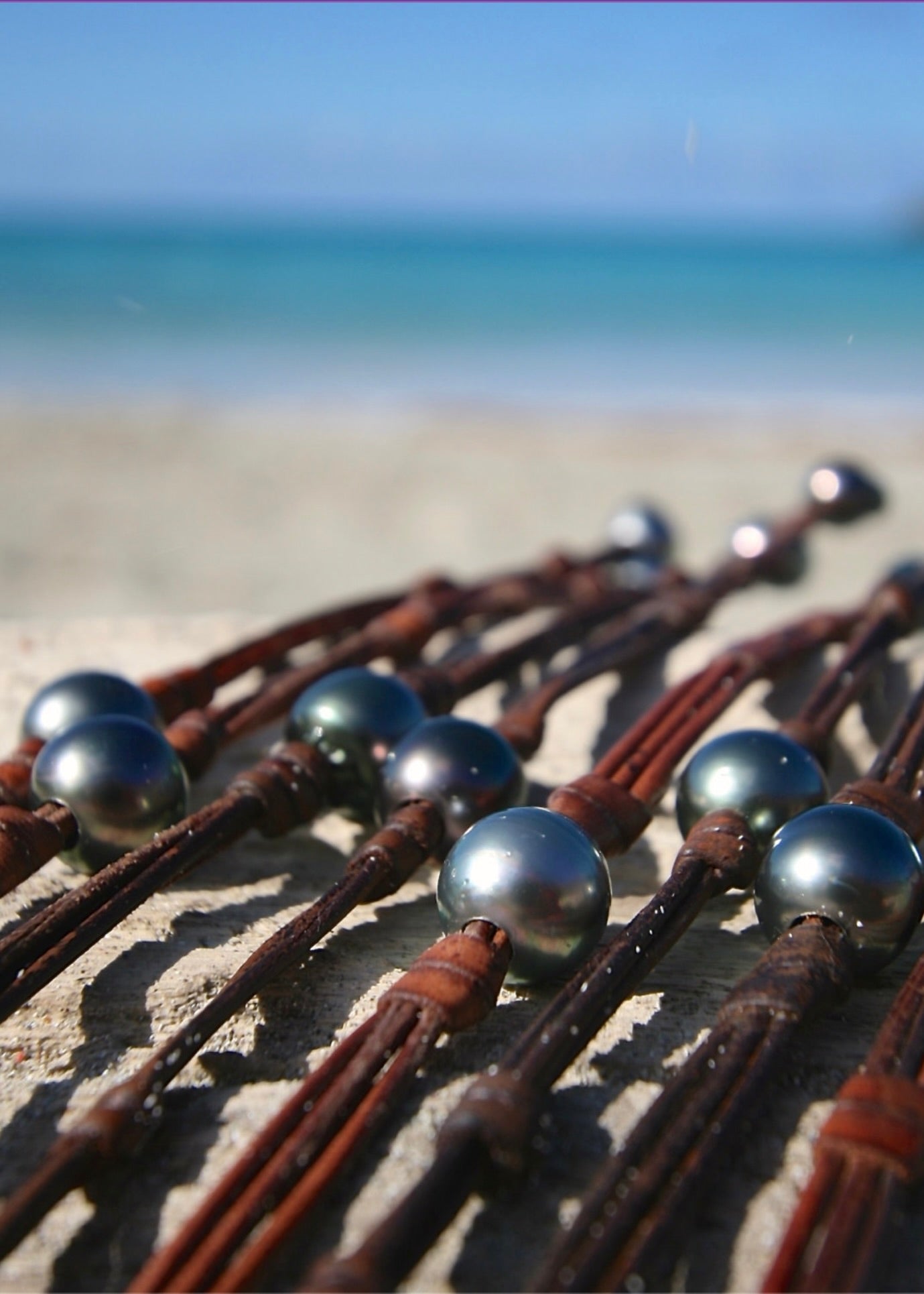 Dark Tahitian pearl on kangaroo leather cord with sailor knot detail on driftwood at Caribbean beach