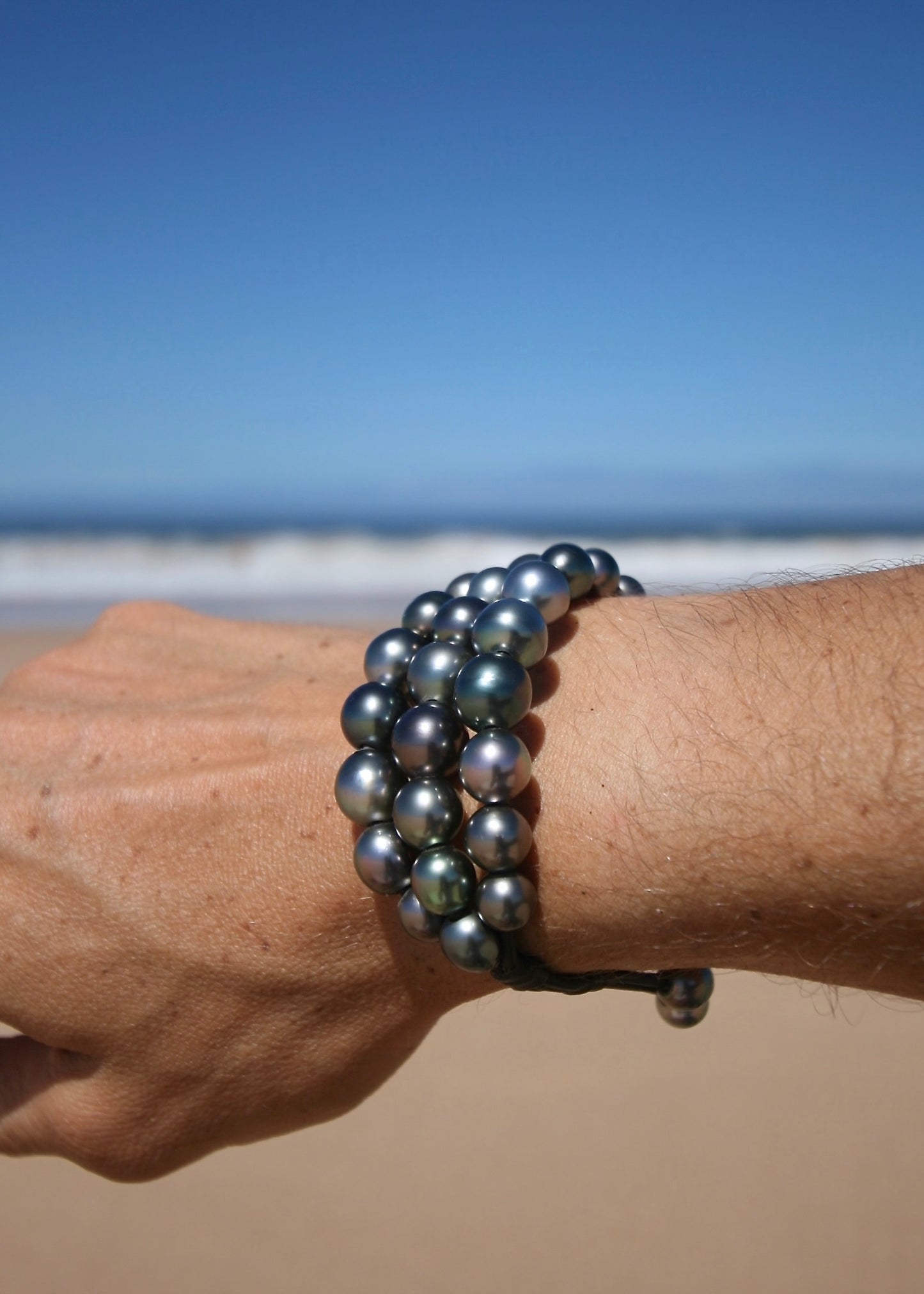Dark Tahitian pearl triple strand bracelet worn on wrist showing bold volume and peacock overtones